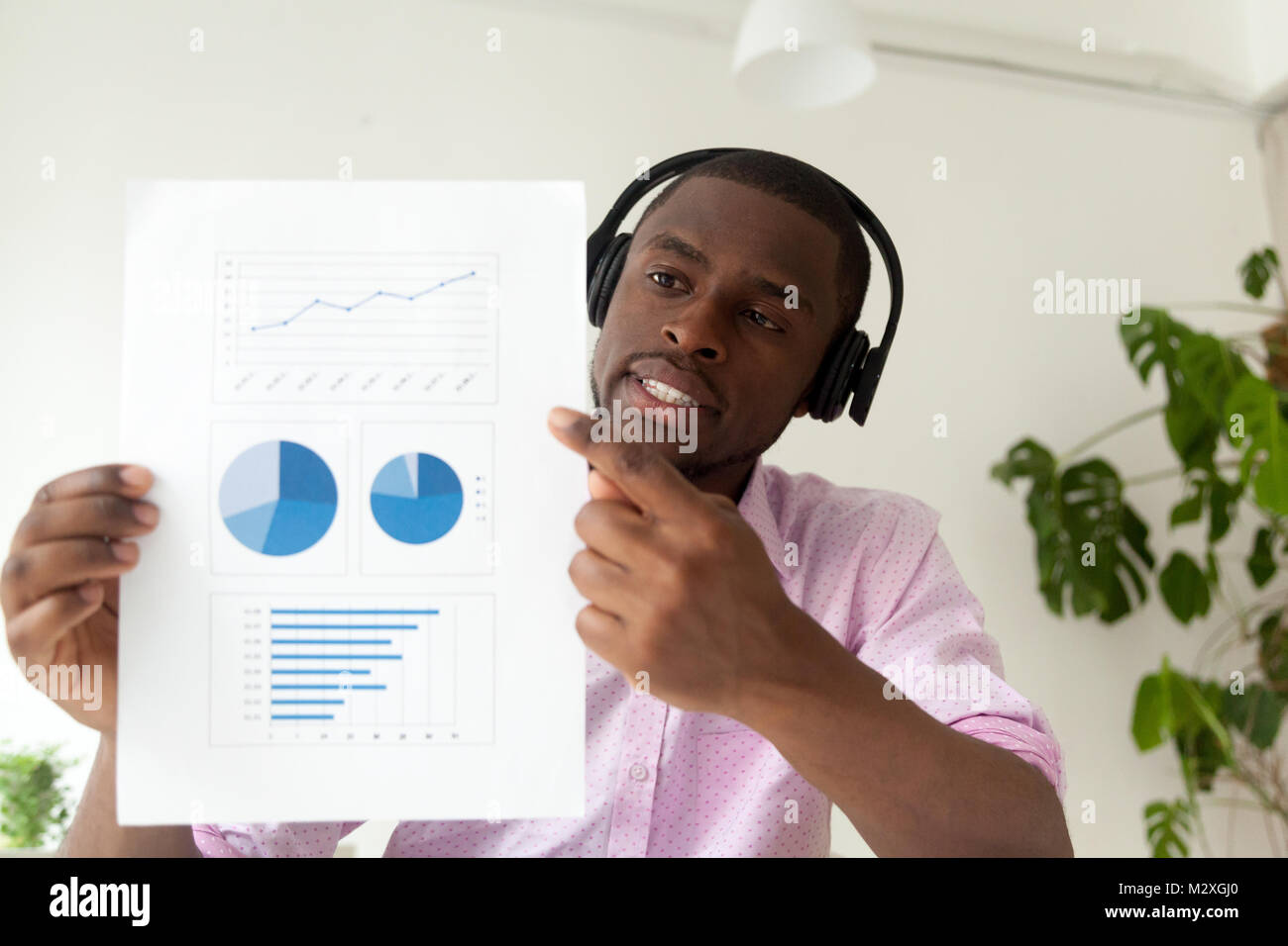 African american businessman in headphones talking by business corporate video call showing infographic statistics, black man holding document with gr Stock Photo