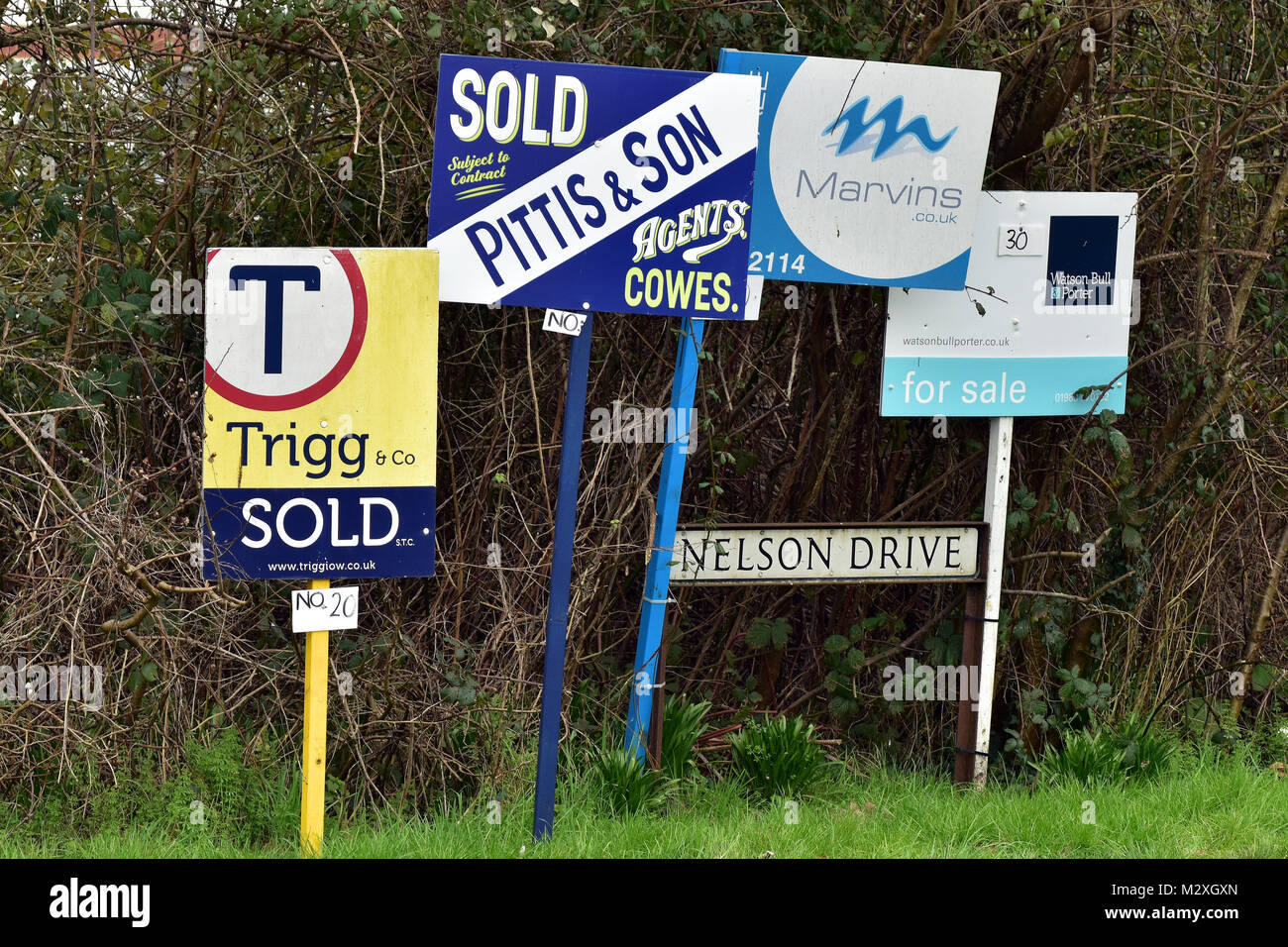 a number of estate agents sold and for sale signs on poles at the end of a street indicating a buoyant and and active property market. selling and buy Stock Photo