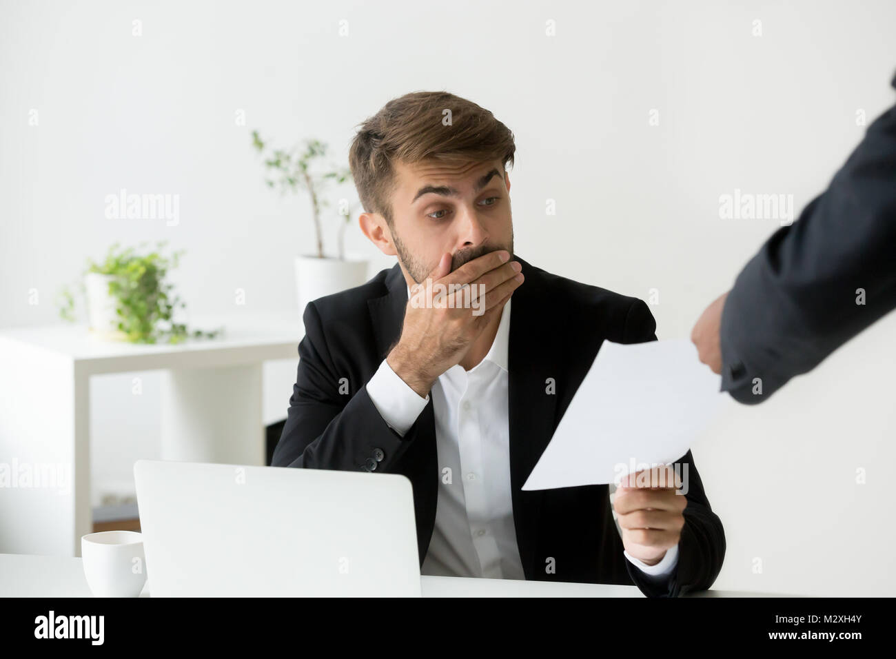 Surprised confused caucasian employee receiving dismissal notice Stock Photo