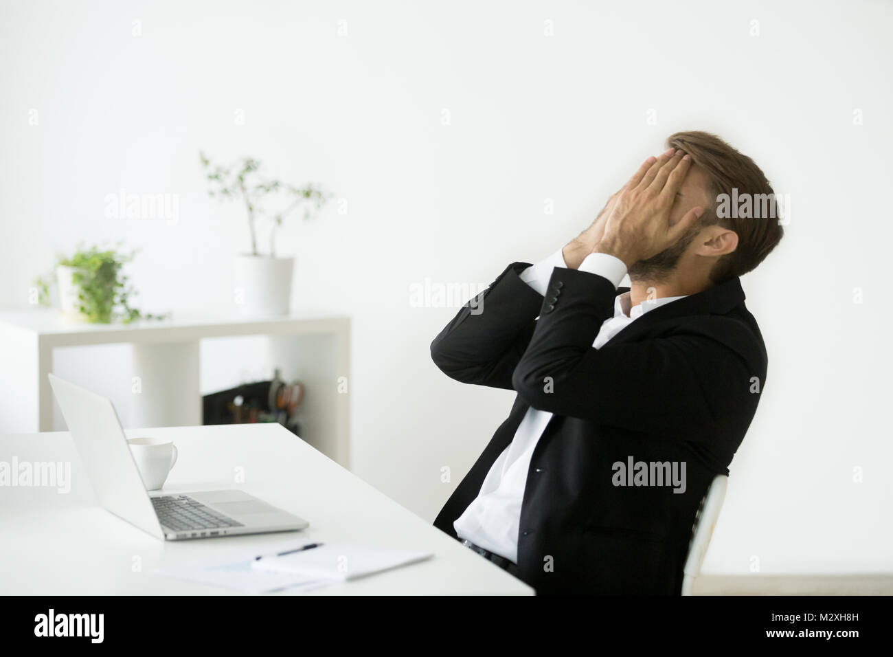 Distraught stressed bankrupt businessman covering face with hand Stock Photo