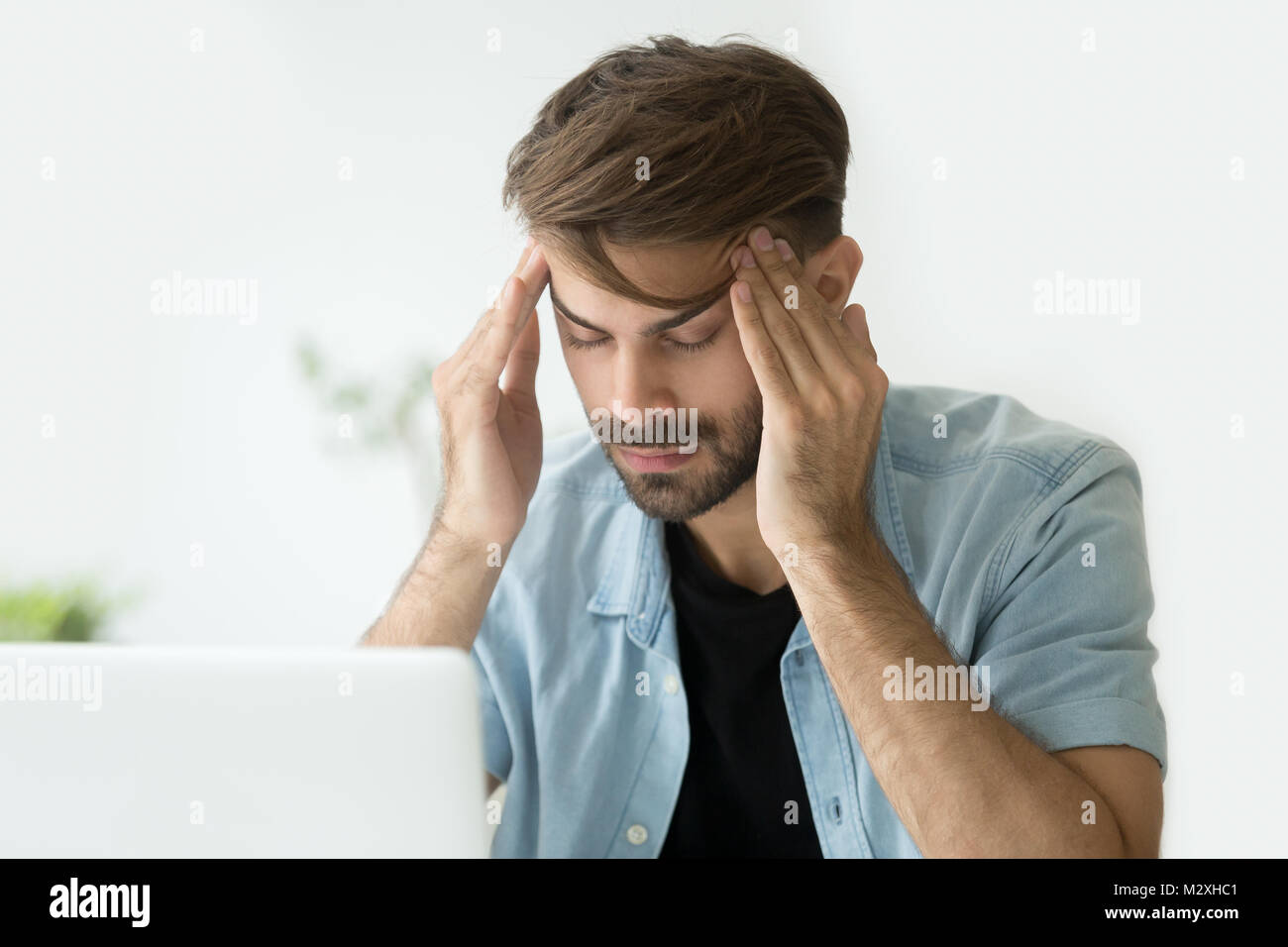 Young man touching temples trying to focus or feeling headache Stock Photo