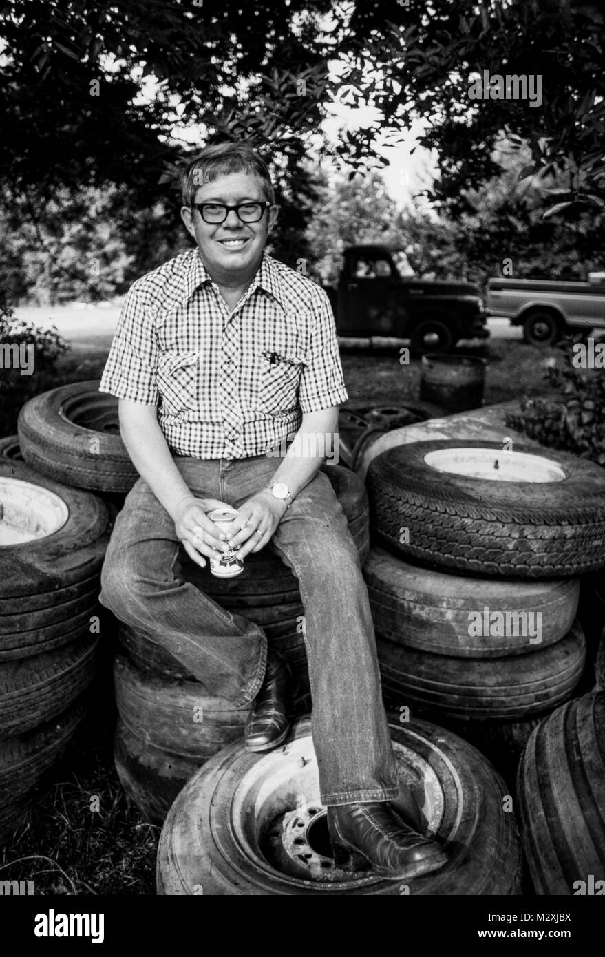 Billy Carter sits on a pile of old tires at his gas station. He was an American farmer and businessman and the younger brother of Pres.  Jimmy Carter. Stock Photo