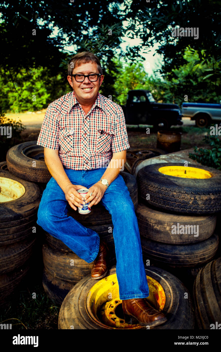 Billy Carter sits on a pile of old tires at his gas station. He was an American farmer and businessman and the younger brother of Pres.  Jimmy Carter. Stock Photo