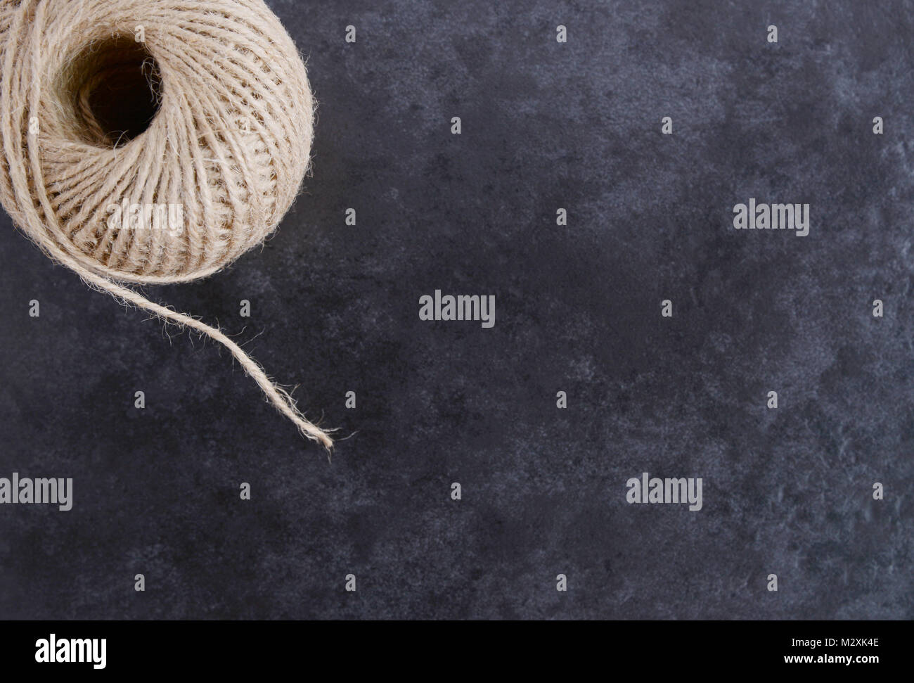 Ball of twine from above, unwinding on a mottled grey background with copy space Stock Photo