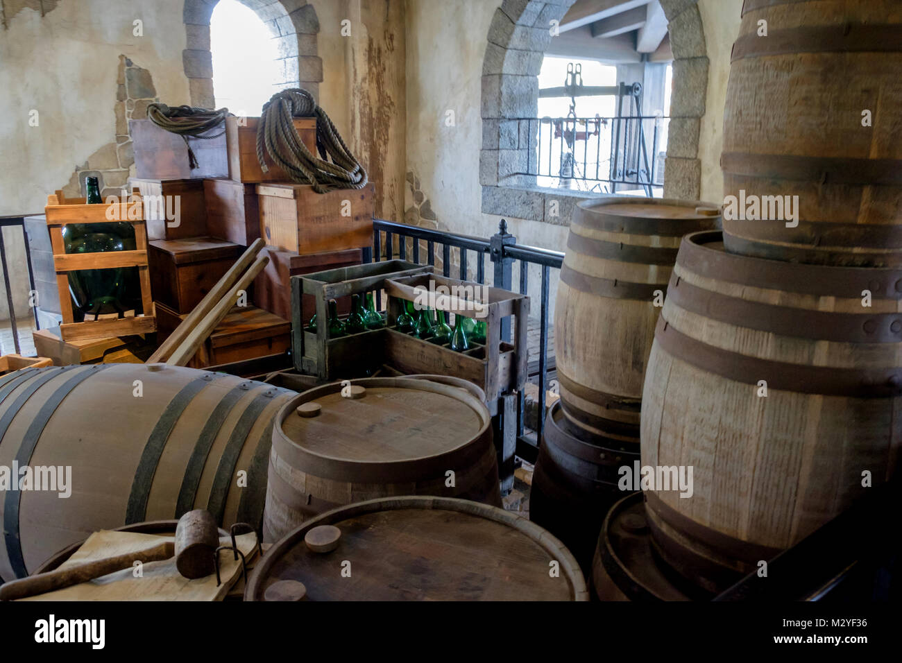 Rustic storage room with arched windows full of old wooden barrels