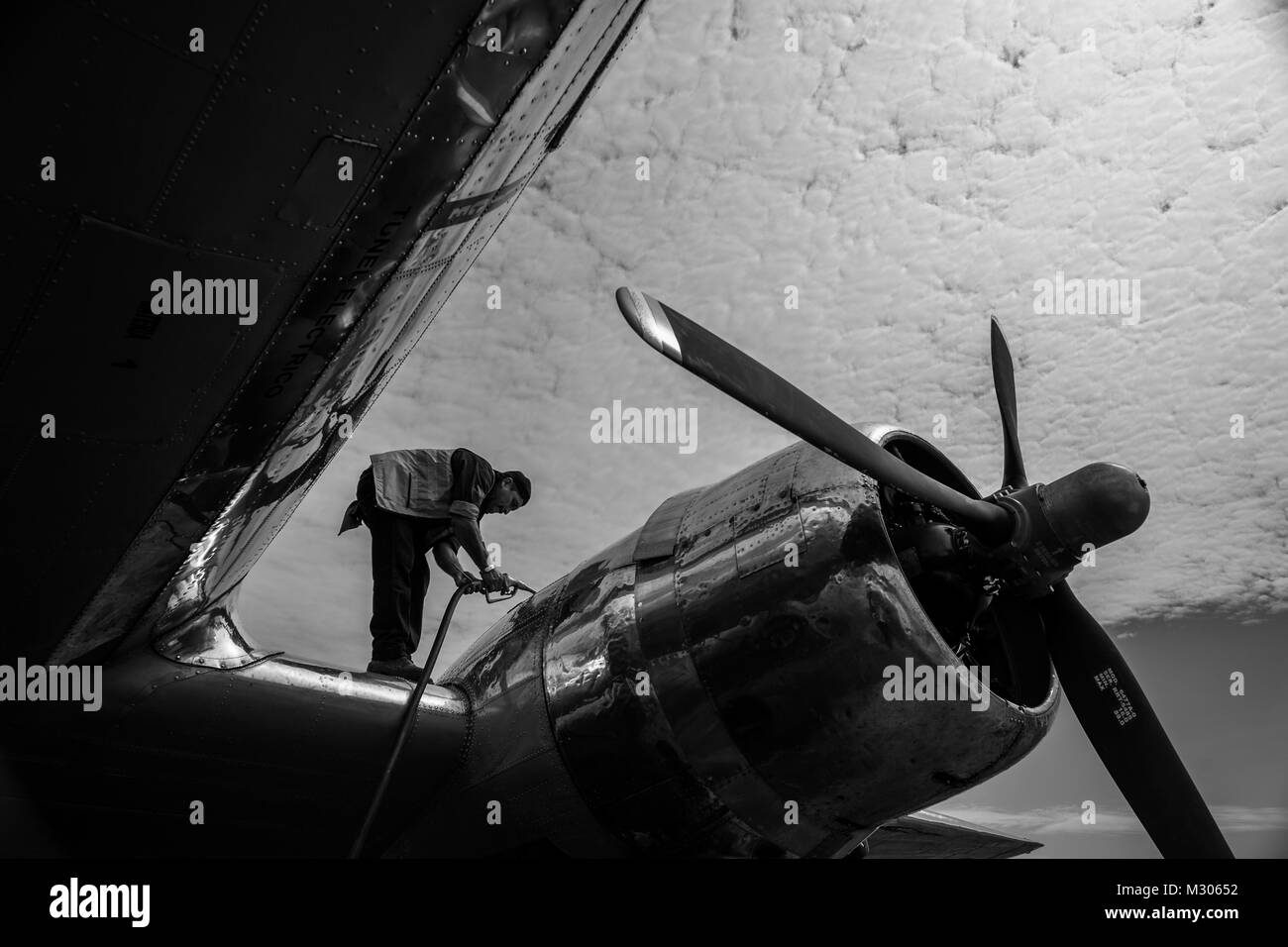 A Colombian mechanic refuels a Douglas DC-3 aircraft at the airport of Puerto Inírida, Colombia. Stock Photo