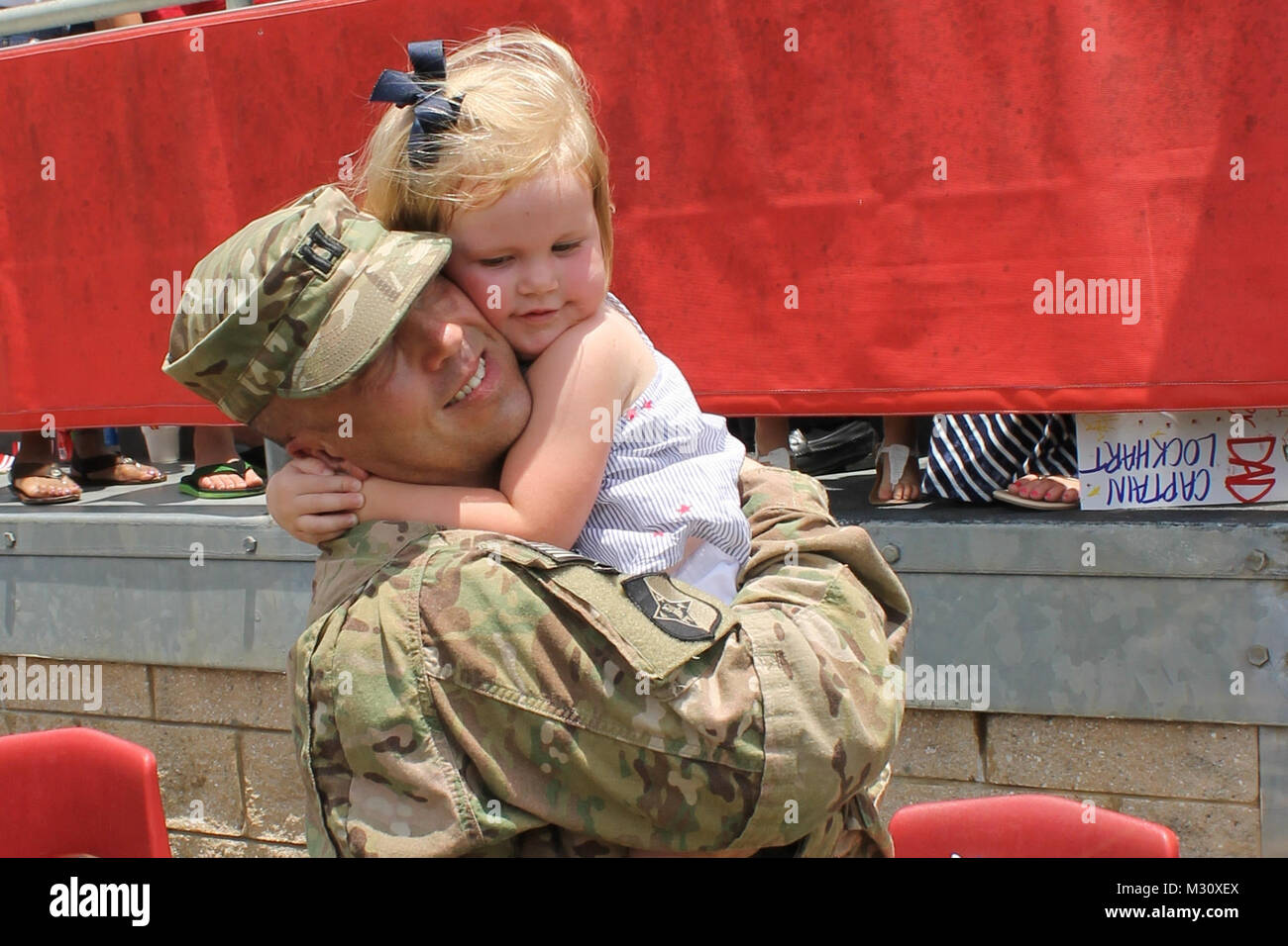 Capt. Brantley Lockhart, commander of the 1230th Transportation Company, hugs his daughter after the 1230th return ceremony at the Thomasville High School's football field May 31. The 1230th drove over 220,000 miles during their eleven month deployment to Afghanistan.  Georgia Army National Guard Photo by Maj. Will Cox | Released Home at last by Georgia National Guard Stock Photo