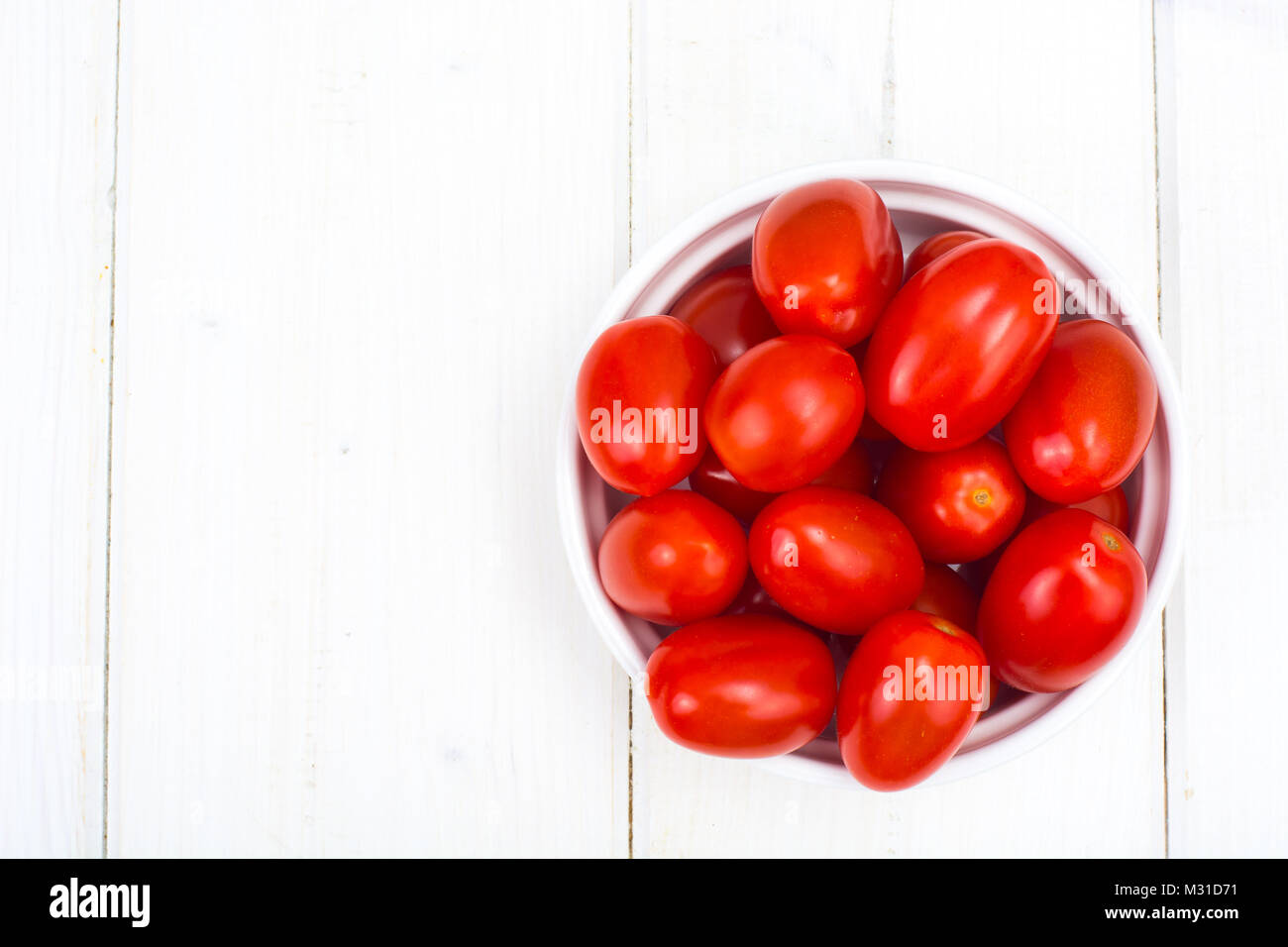 Small red ripe tomatoes in bowl on wooden table, top view Stock Photo ...