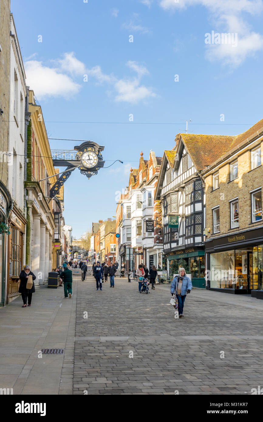 People walking along Winchester High Street with Winchester high street clock on a bright day with blue sky in Winchester 2018, Hampshire, England, UK Stock Photo