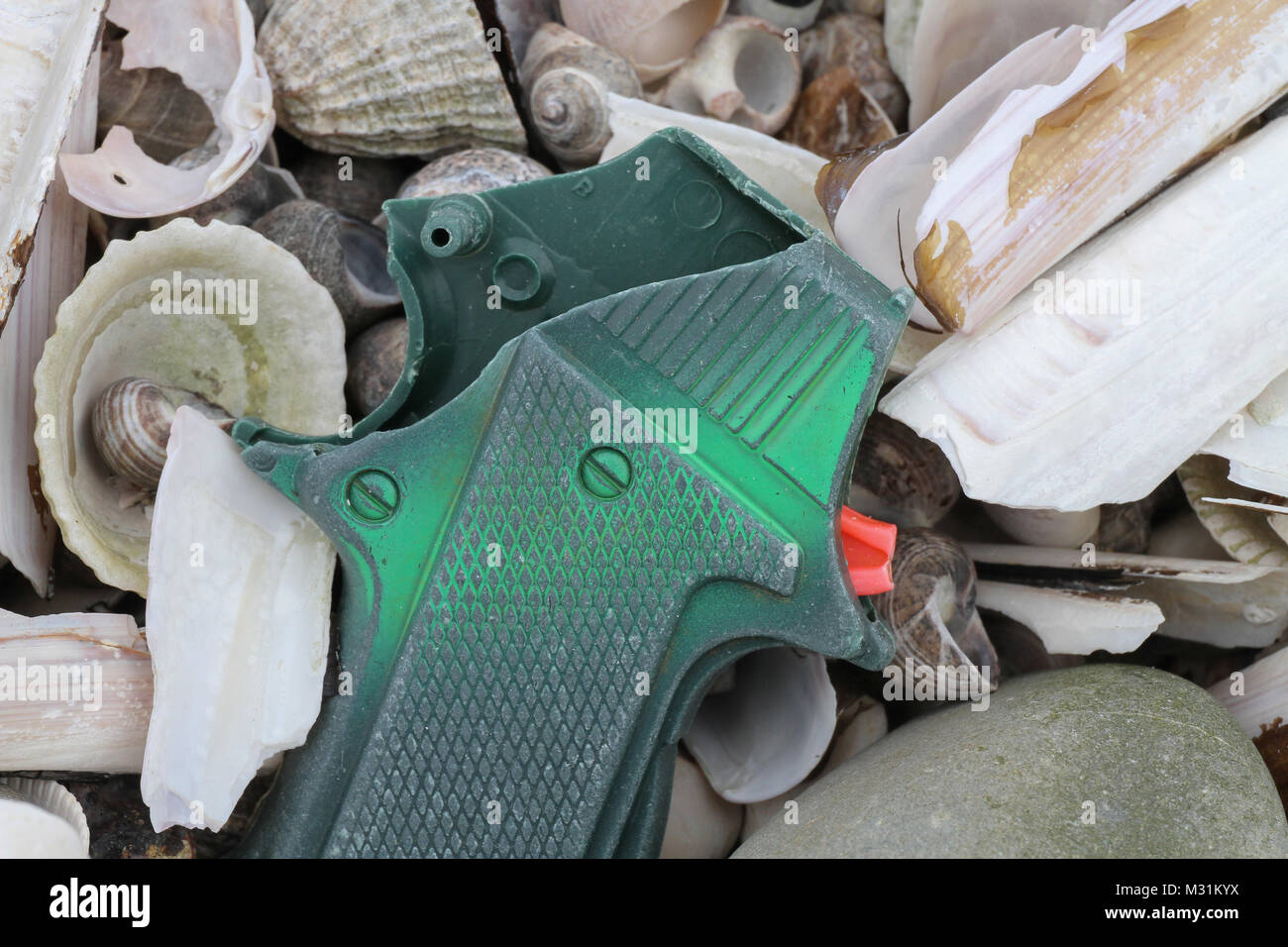 Plastic in the sea. Part of a plastic toy gun lying on shells on a UK beach Stock Photo Alamy