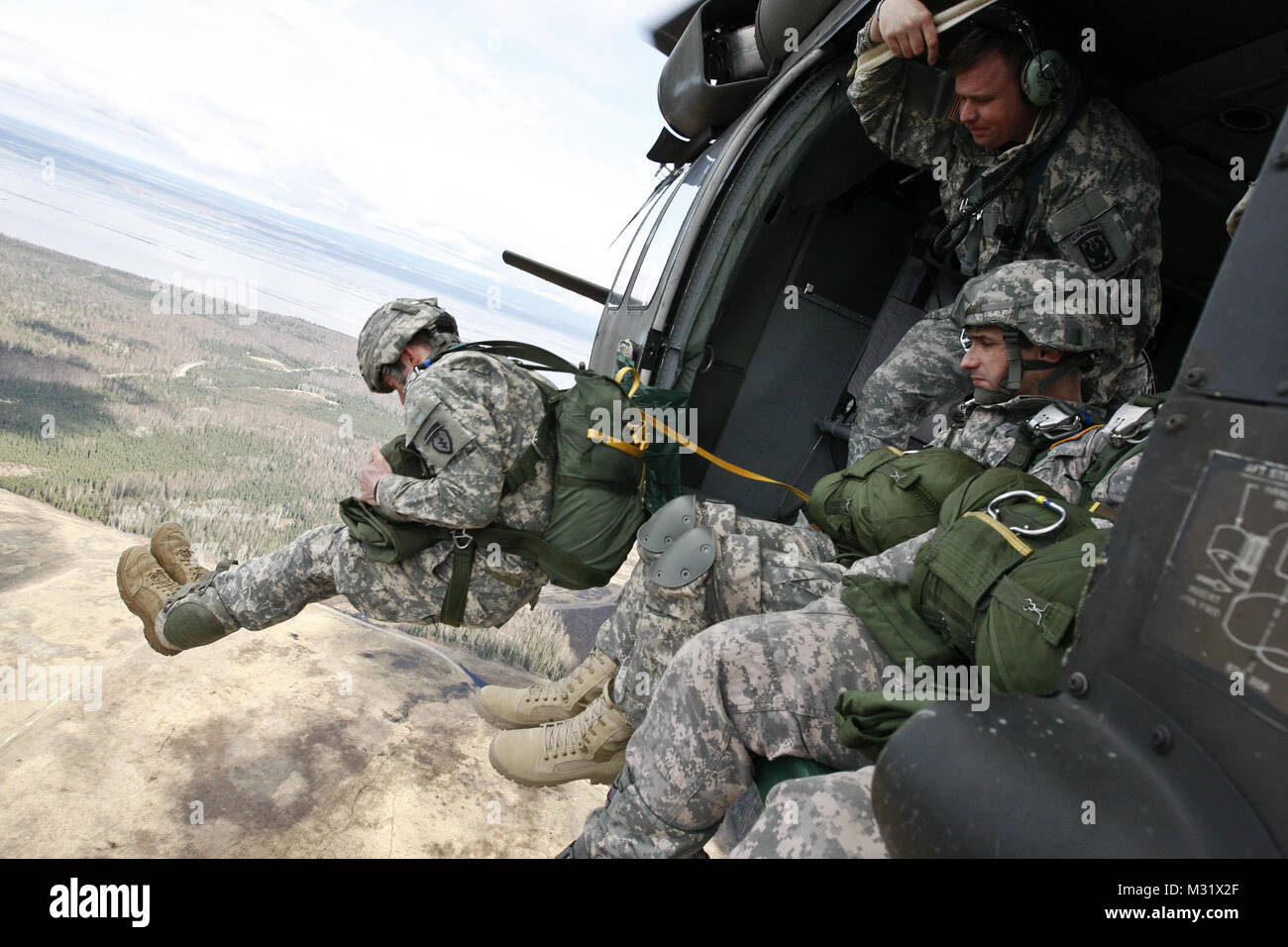 Soldiers attending the Mobile Pathfinder Course parachute from a UH-60 Black Hawk onto Malamute Drop Zone, May 23, 2013. More than 40 soldiers put their skills to the test as pilots and crews from the 1st Battalion, 207th Aviation Regiment, Alaska Army National Guard, provided aviation support. The three-week course, conducted by cadre from Headquarters and Headquarters Company, 1st Battalion, 507th Parachute Infantry Regiment (U.S. Army Pathfinder School), Fort Benning, Ga., instructs students in air traffic control, medical evacuation operations, sling load operations, helicopter landing zon Stock Photo