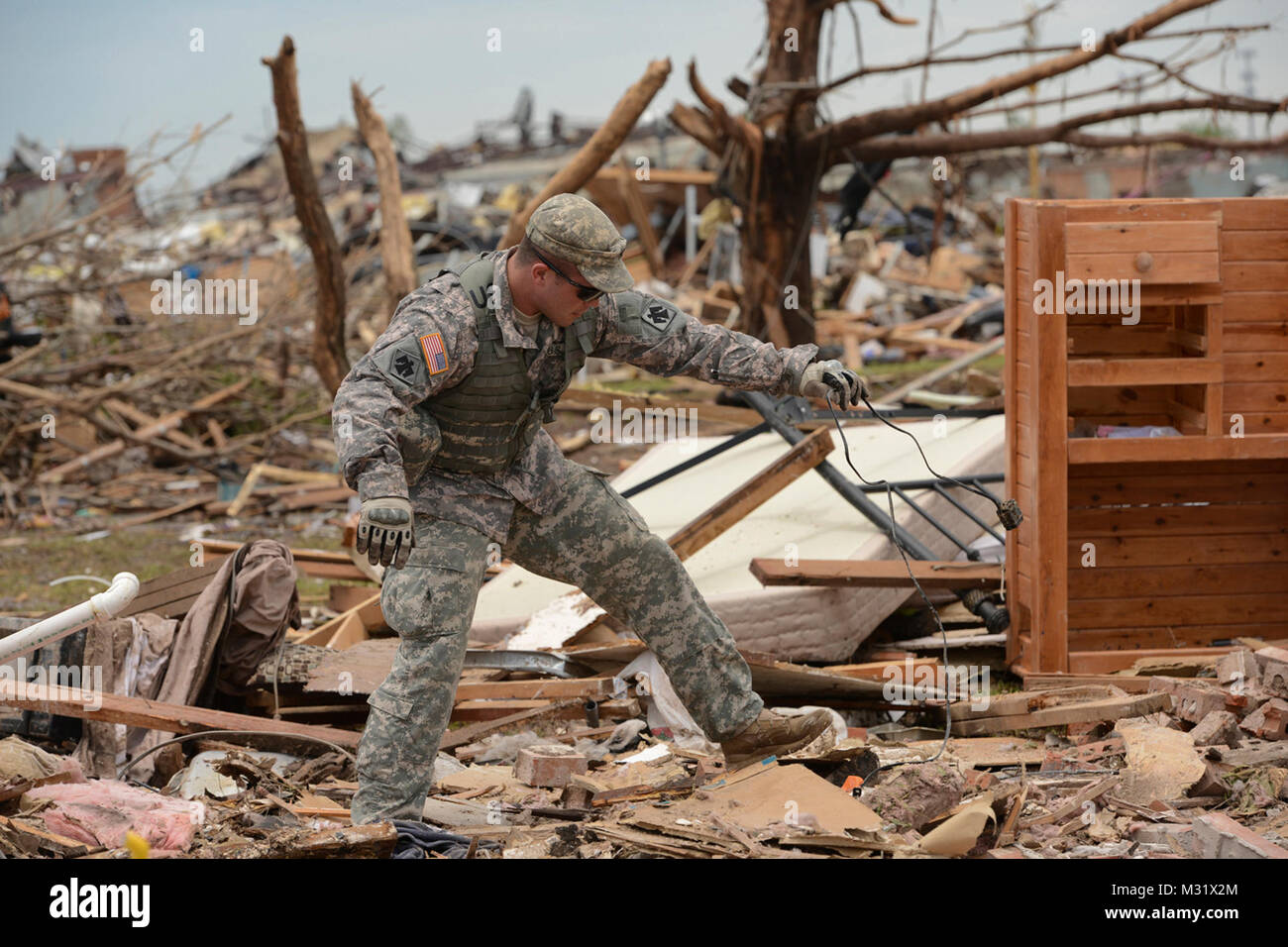 Oklahoma Army National Guardsman, Spc. Eric Walker with Headquarters Company, 1st Battalion, 179th Infantry, 45th Infantry Brigade Combat Team, help residents comb through the rubble of their demolished house looking for their laptop computer in hopes of salvaging irreplaceable data. The Moore, Okla., neighborhood was devastated on May 20th, 2013, by an F5 tornado. Spc Walker was tasked with community presence patrol, providing help and relief where needed.   (U.S. Air National Guard photo by Master Sgt. Mark Moore/Released) 130523-Z-BI488-137 by Oklahoma National Guard Stock Photo
