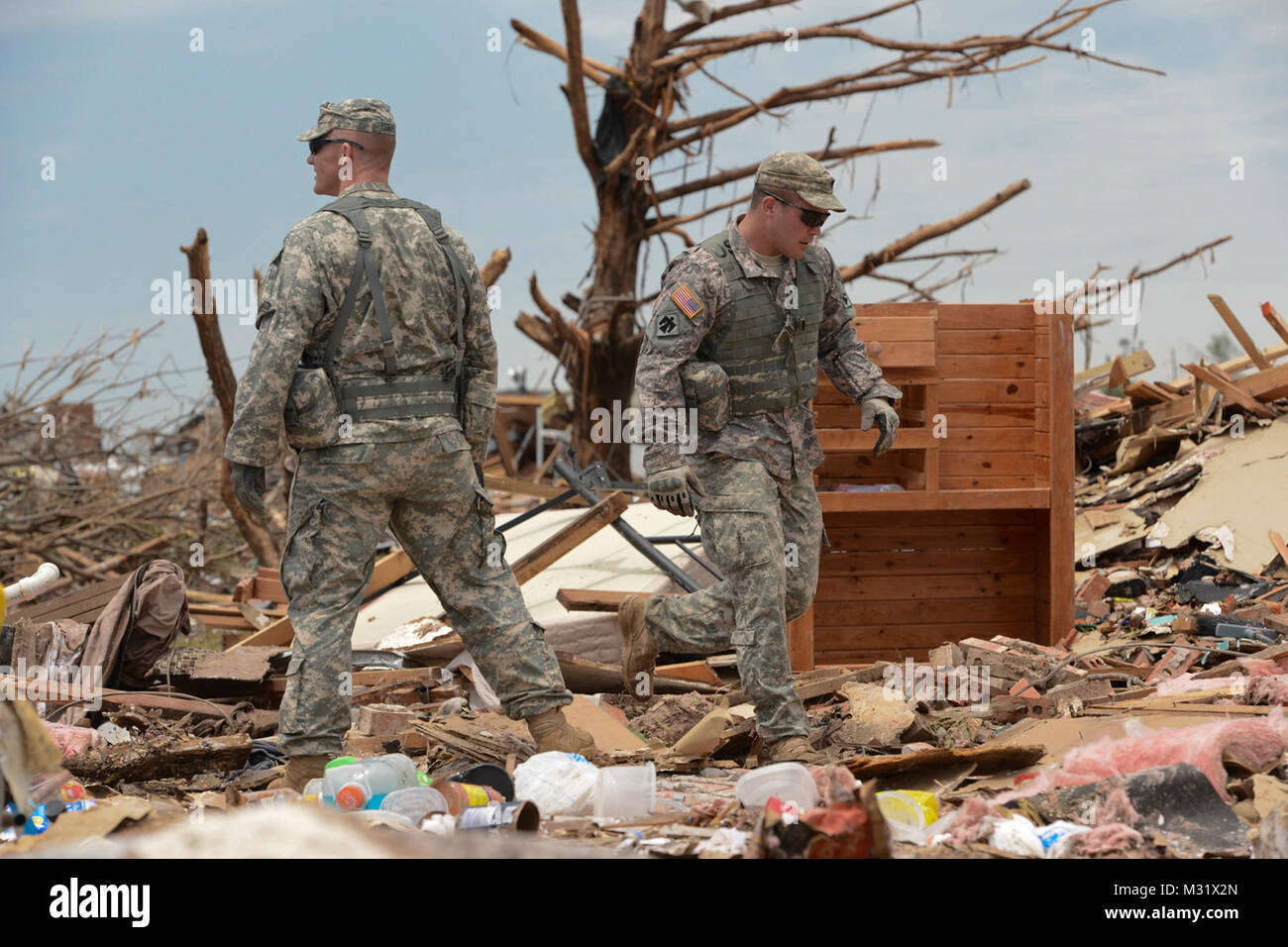 Oklahoma Army National Guardsmen, Spc. Eric Walker and Staff Sgt. Larry Isbell with Headquarters Company, 1st Battalion, 179th Infantry, 45th Infantry Brigade Combat Team, help residents comb through the rubble of their demolished house looking for their laptop computer in hopes of salvedging irrreplacable data. The Moore, Okla., neighborhood was devastated on May 20th, 2013, by an F5 tornado. Walker and Isbell were tasked to a community presence patrol and provided help and relief as needed.   (U.S. Air National Guard photo by Master Sgt. Mark Moore/Released) Community Presence Patrols 004 by Stock Photo
