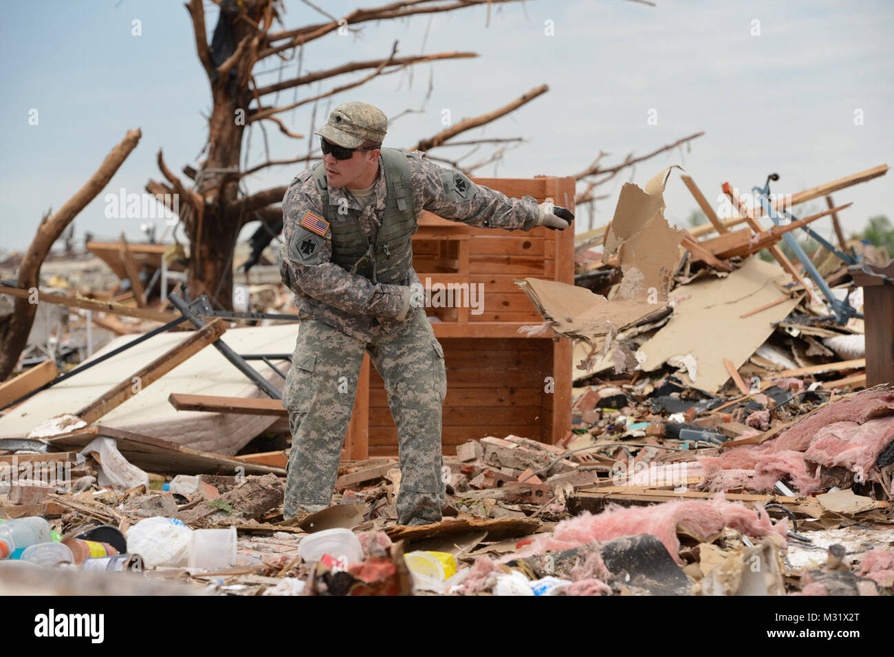 Oklahoma Army National Guardsman, Spc. Eric Walker with Headquarters Company, 1st Battalion, 179th Infantry, 45th Infantry Brigade Combat Team, helps residents comb through the rubble of their demolished home looking for their laptop computer in hopes of salvaging irreplaceable data. The Moore, Okla., neighborhood was devastated on May 20th, 2013, by an F5 tornado. Spc Walker was tasked to a community presence patrol, providing help and relief as needed.   (U.S. Air National Guard photo by Master Sgt. Mark Moore/Released) Community Presence Patrols 005 by Oklahoma National Guard Stock Photo
