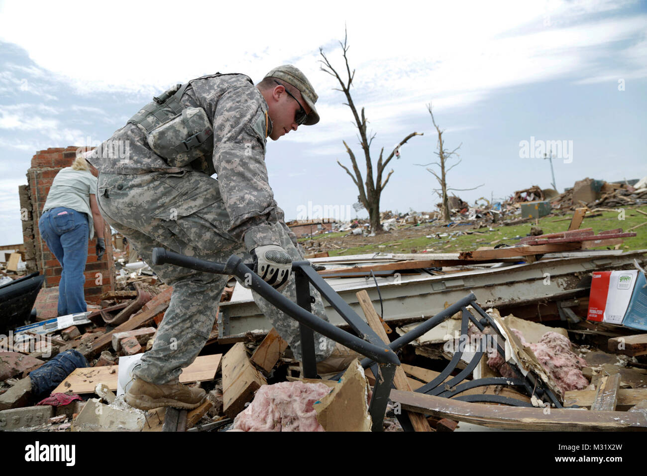 Oklahoma Army National Guardsman, Spc. Eric Walker with Headquarters Company, 1st Battalion, 179th Infantry, 45th Infantry Brigade Combat Team, helps residents comb through the rubble of their demolished home looking for their laptop computer in hopes of salvaging irreplaceable data. The Moore, Okla., neighborhood was devastated on May 20th, 2013, by an F5 tornado. Spc Walker was tasked to a community presence patrol, providing help and relief as needed.   (U.S. Air National Guard photo by Master Sgt. Mark Moore/Released) Community Presence Patrols 006 by Oklahoma National Guard Stock Photo