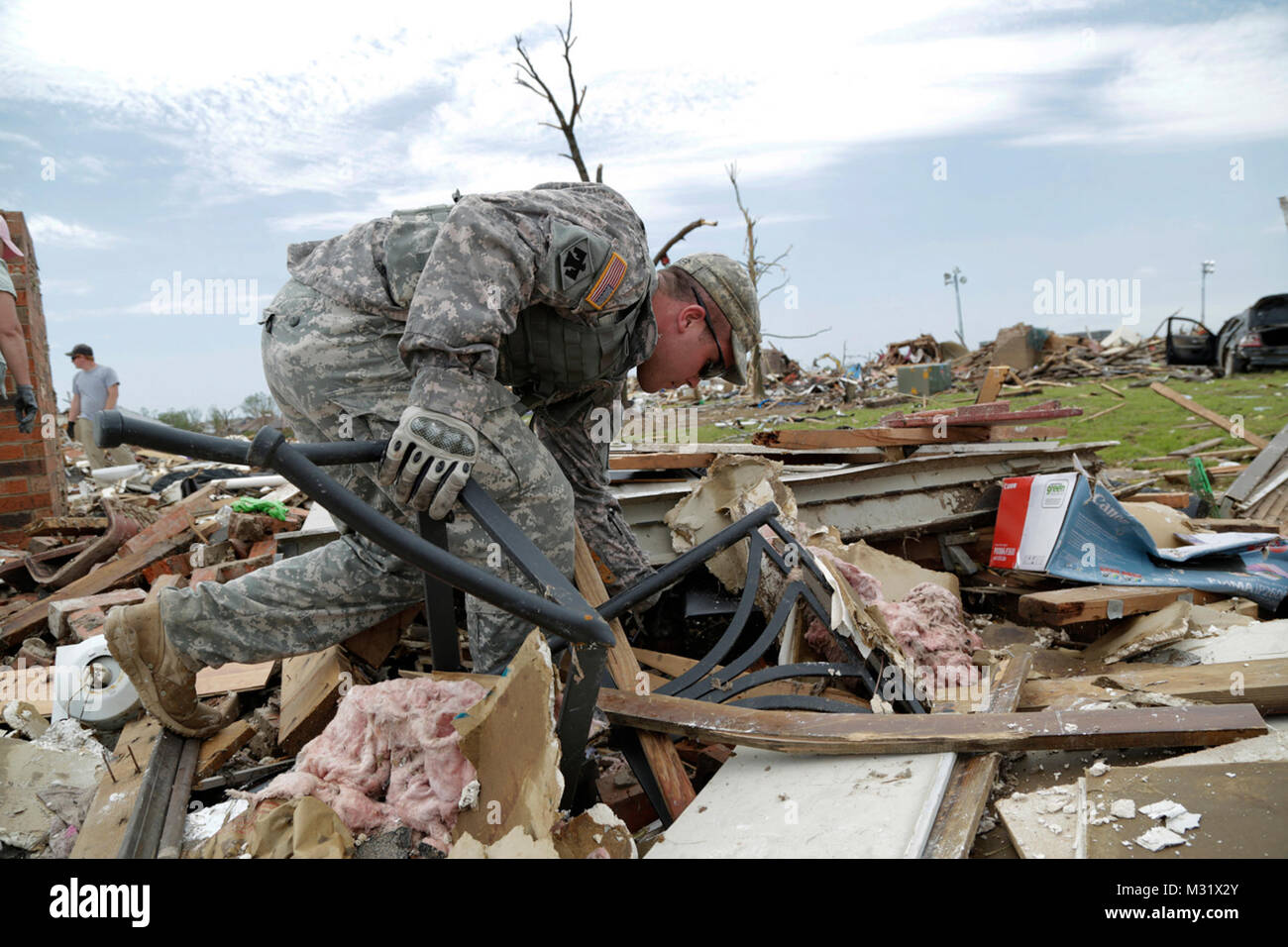 Oklahoma Army National Guardsman, Spc. Eric Walker with Headquarters Company, 1st Battalion, 179th Infantry, 45th Infantry Brigade Combat Team, helps residents comb through the rubble of their demolished home looking for their laptop computer in hopes of salvaging irreplaceable data. The Moore, Okla., neighborhood was devastated on May 20, 2013, by an F5 tornado. Spc Walker was tasked to a community presence patrol, providing help and relief as needed.   (U.S. Air National Guard photo by Master Sgt. Mark Moore/Released) Community Presence Patrols 007 by Oklahoma National Guard Stock Photo