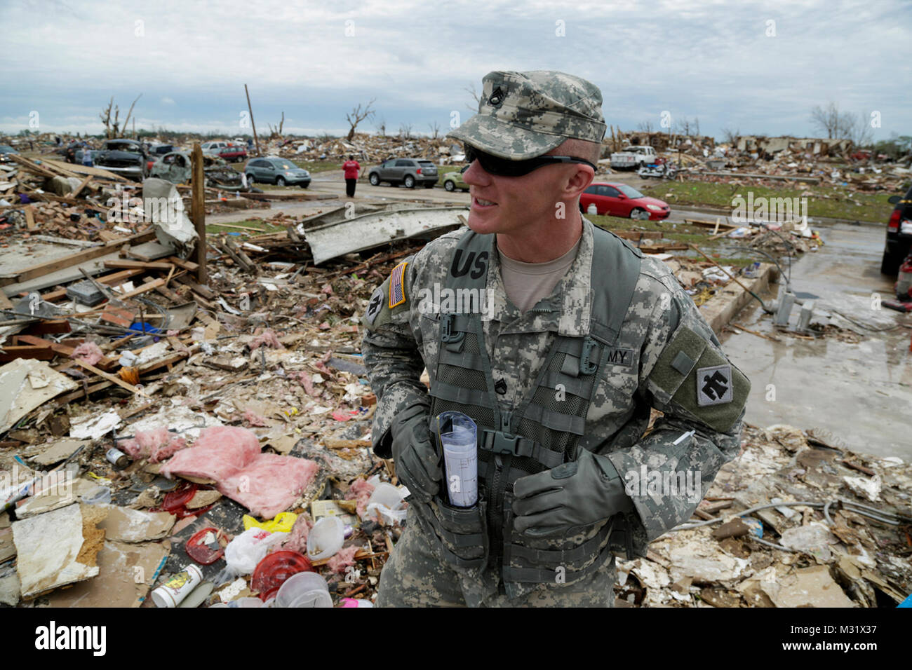 Oklahoma Army National Guardsman, Staff Sgt. Larry Isbell with Headquarters Company, 1st Battalion, 179th Infantry, 45th Infantry Brigade Combat Team, talks with a resident while taking a break from combing through the rubble of their demolished house while looking for their laptop computer in hopes of salvaging irreplaceable data. The Moore, Oklahoma neighborhood was devastated on May 20, 2013, by an F5 tornado. Isbell was tasked to a community presence patrol, providing help and relief as needed.   (U.S. Air National Guard photo by Master Sgt. Mark Moore/Released) Community Presence Patrols  Stock Photo
