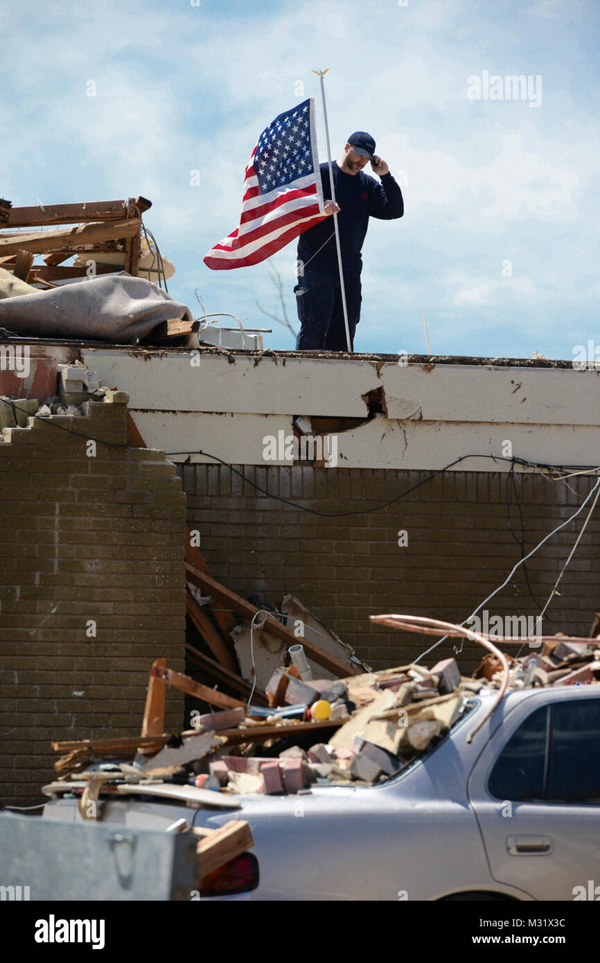 A resident of a Moore, Okla., neighborhood, which was devastated on May 20, 2013, by an F5 tornado, raises a U. S. flag above his devastated home. Many such symbolic gestures could be seen throughout the mile wide, 18 mile long corridor carved by the twister.  (U.S. Air National Guard photo by Master Sgt. Mark Moore/Released) Community Presence Patrols 015 by Oklahoma National Guard Stock Photo