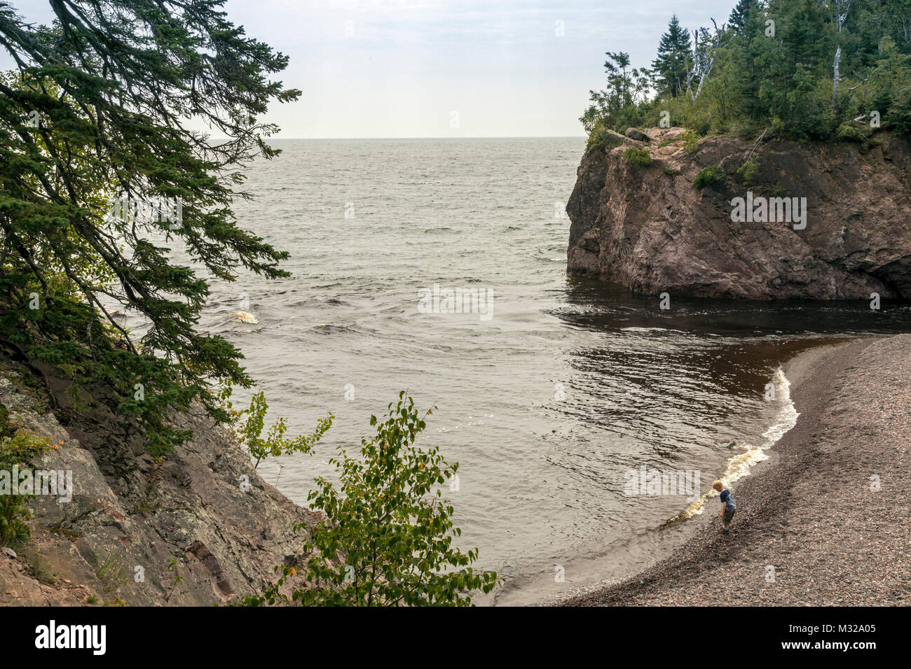 Silver Bay, Minnesota - A boy on the shore of Lake Superior, where the Baptism River enters the lake, in Tettegouche State Park. Stock Photo