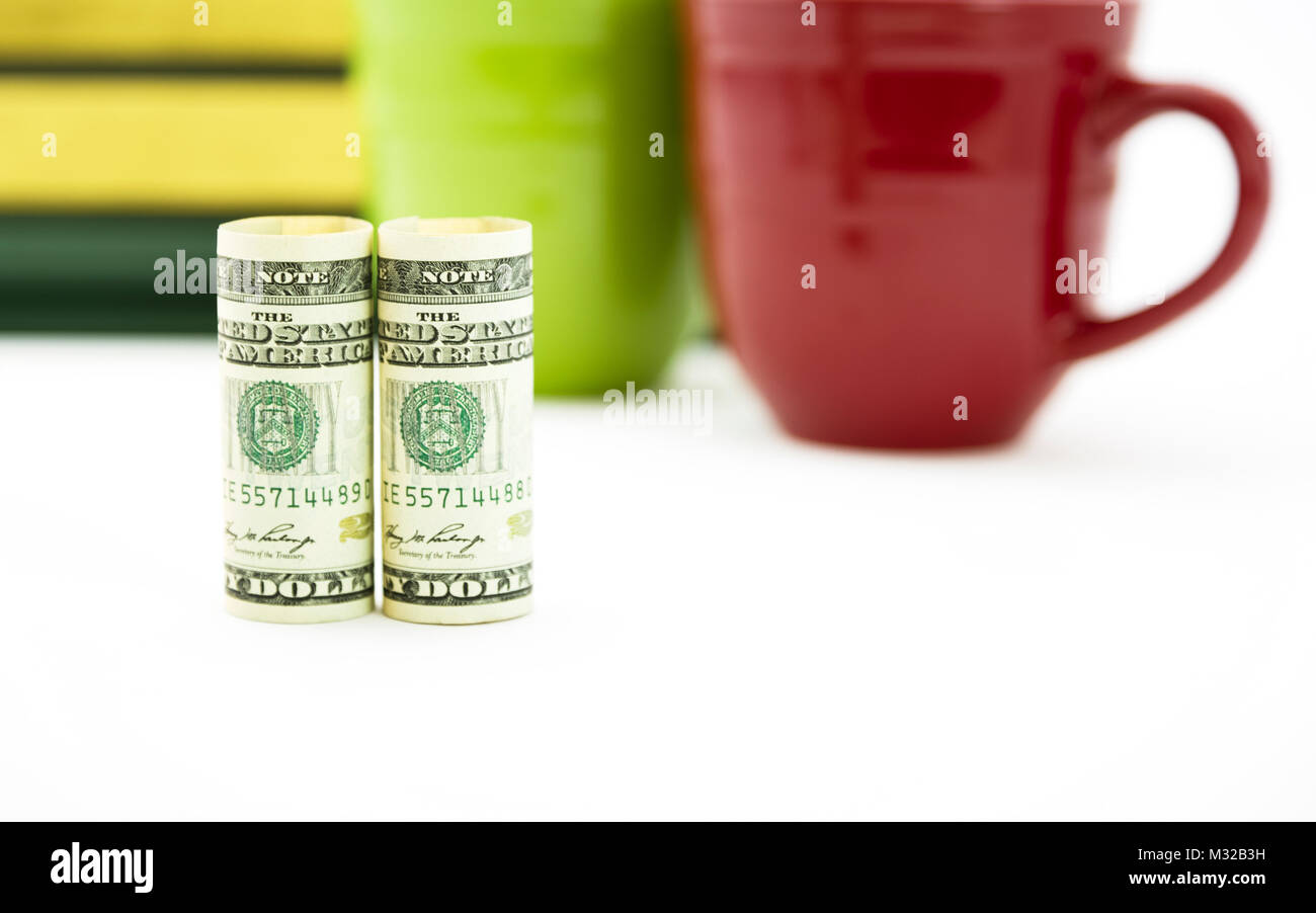 Financial decision making and  thoughtful discussion process emphasized with selective focus on money with red and green mugs and books in background  Stock Photo