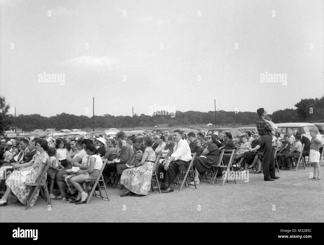 Large group of people are seated outside, ca. 1960. Stock Photo