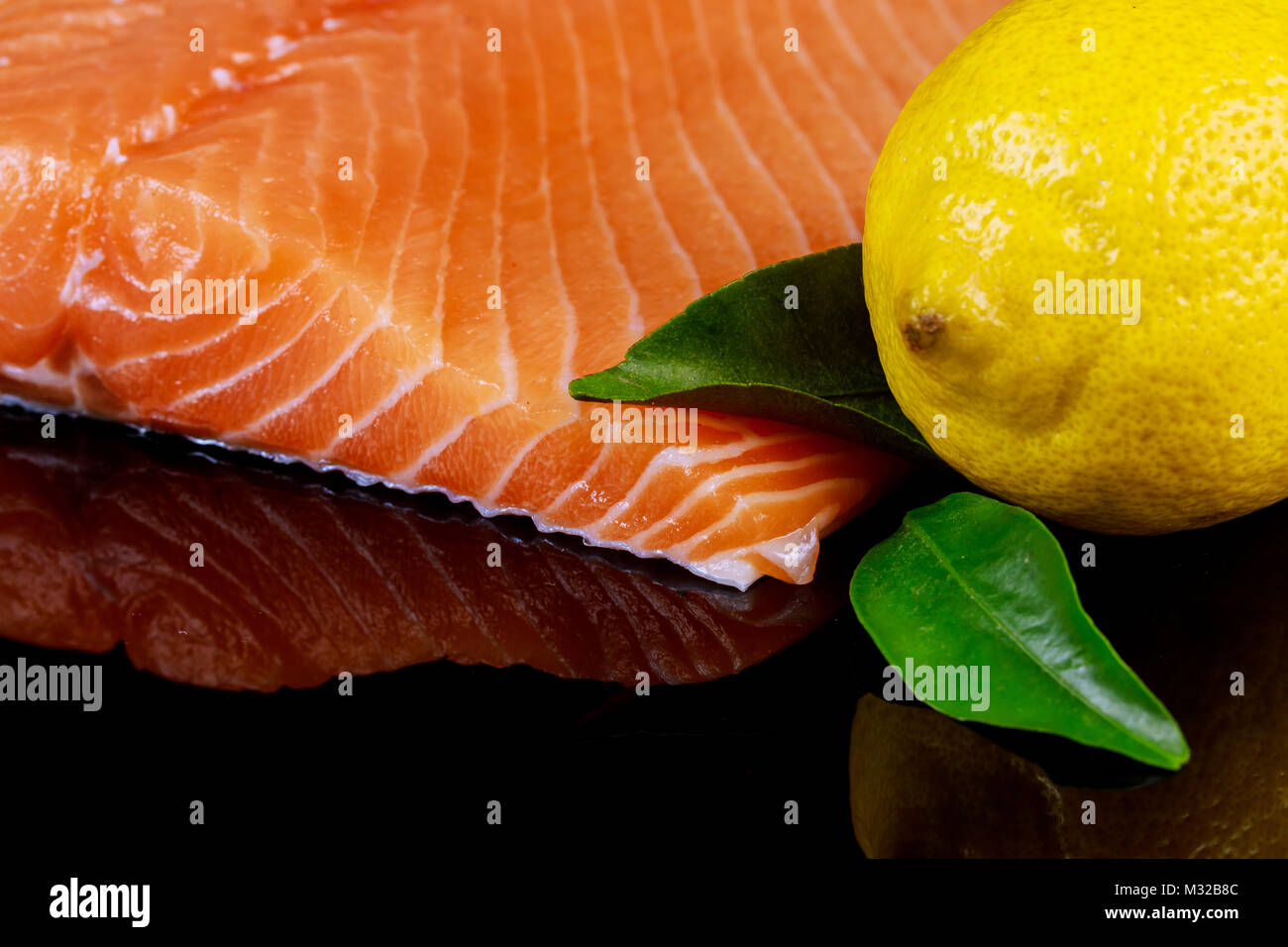 Raw salmon fish fillet and lemon on black background Stock Photo - Alamy