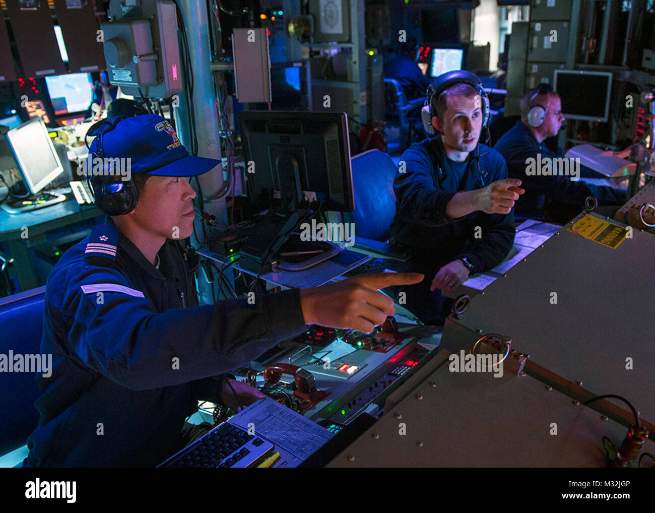 WATERS NEAR GUAM (Mar. 9, 2016) Lt. Thomas Brewer, (right), Chief Engineer of Arliegh Burke-class guided-missile destr160309-N-DJ750-318 WATERS NEAR GUAM (Mar. 9, 2016) Lt. Thomas Brewer, (right), Chief Engineer of Arliegh Burke-class guided-missile destroyer USS McCampbell (DDG 85), and Japan Maritime Self-Defense Force (JMSDF) Lt. Cmdr. Hironori Ikeda, of JMSDF Chief staff, Escort Division 6, discuss tactical data from the Combat Information Center (CIC) during Multi Sail 2016. Multi Sail is a bilateral training exercise aimed at interoperability between the U.S. and Japanese forces. This ex Stock Photo