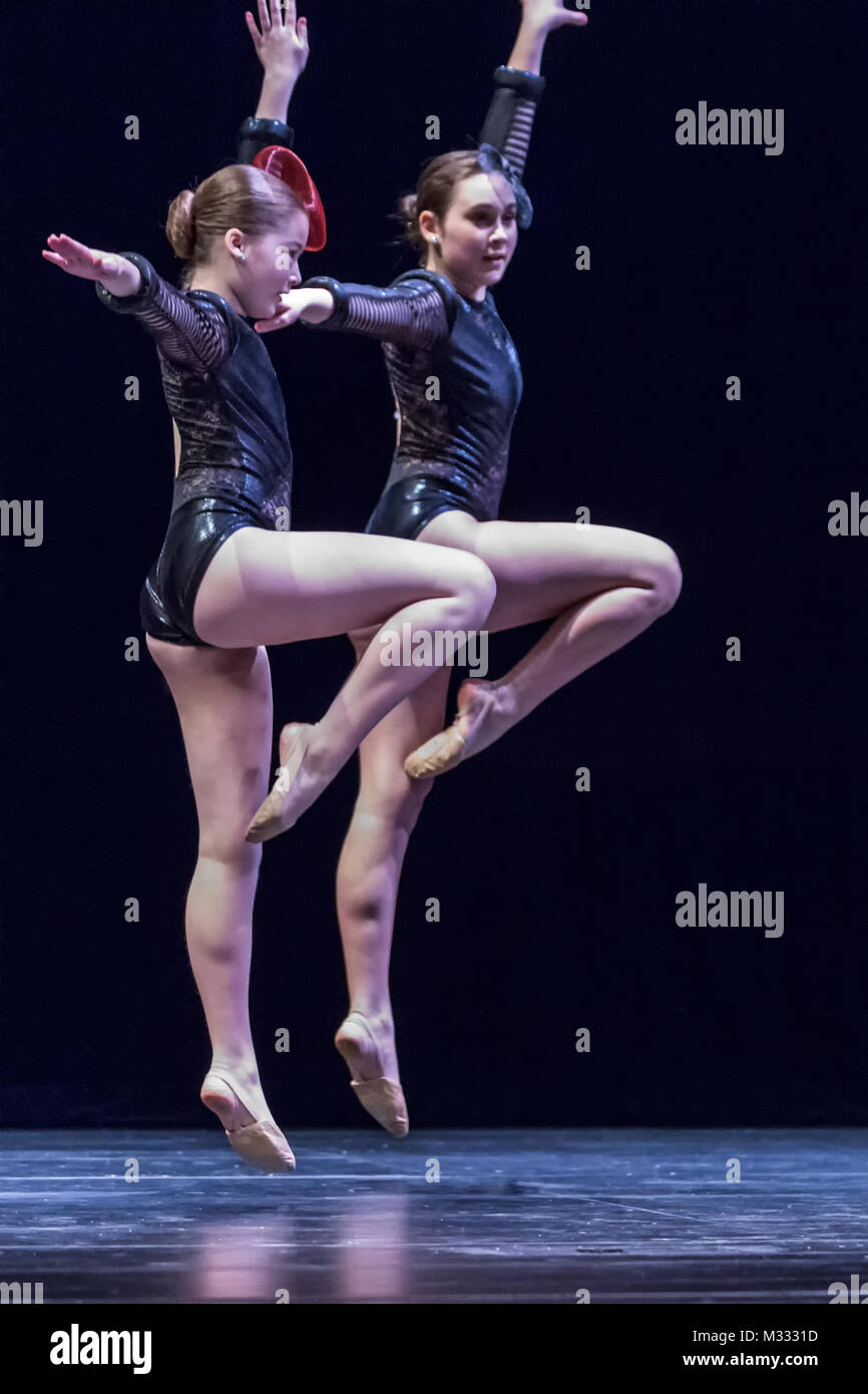 Twelve year old girls dancing onstage doing a pose jump Stock Photo