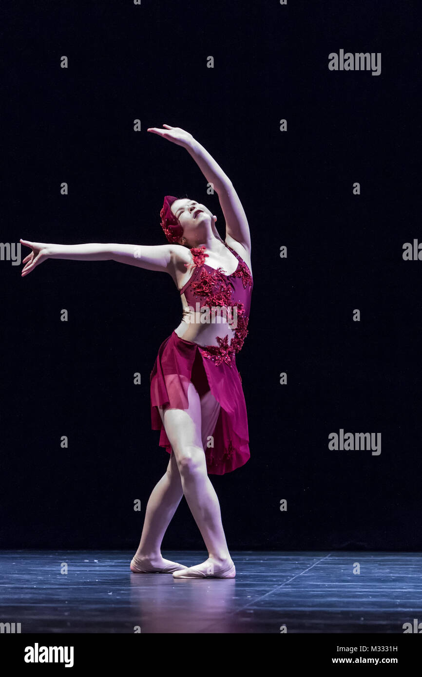 Twelve year old girl performing a solo lyrical dance onstage, doing a fourth position prep with the feet Stock Photo
