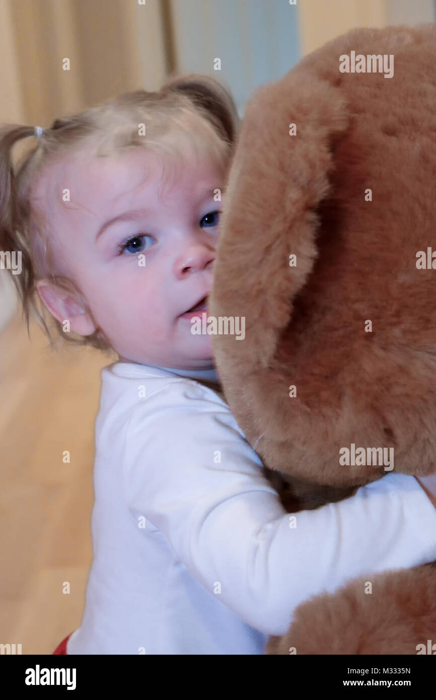 13-month old girl hugging a large stuffed bear Stock Photo