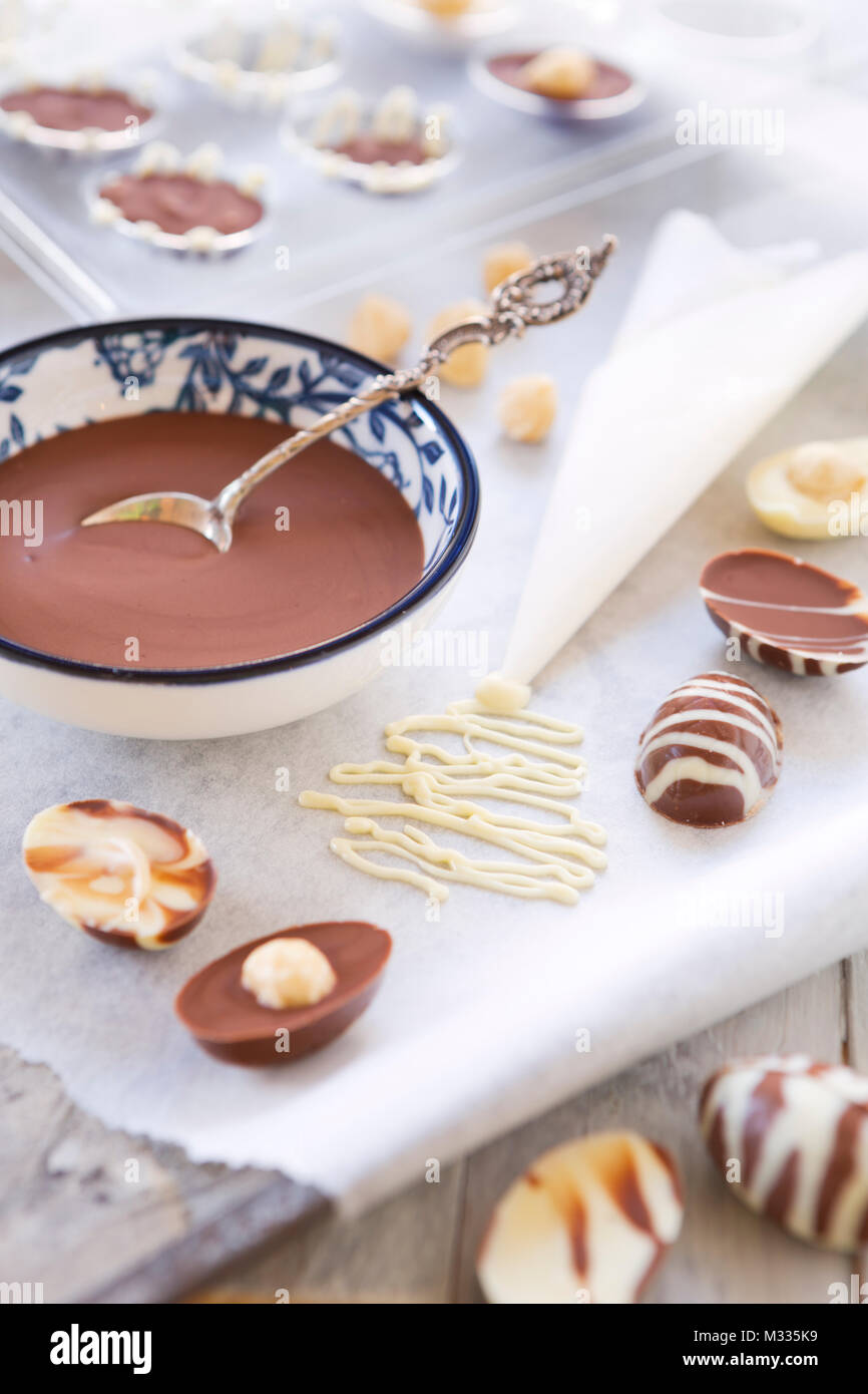 Homemade milk and white chocolate Easter eggs on a rustic table. Stock Photo