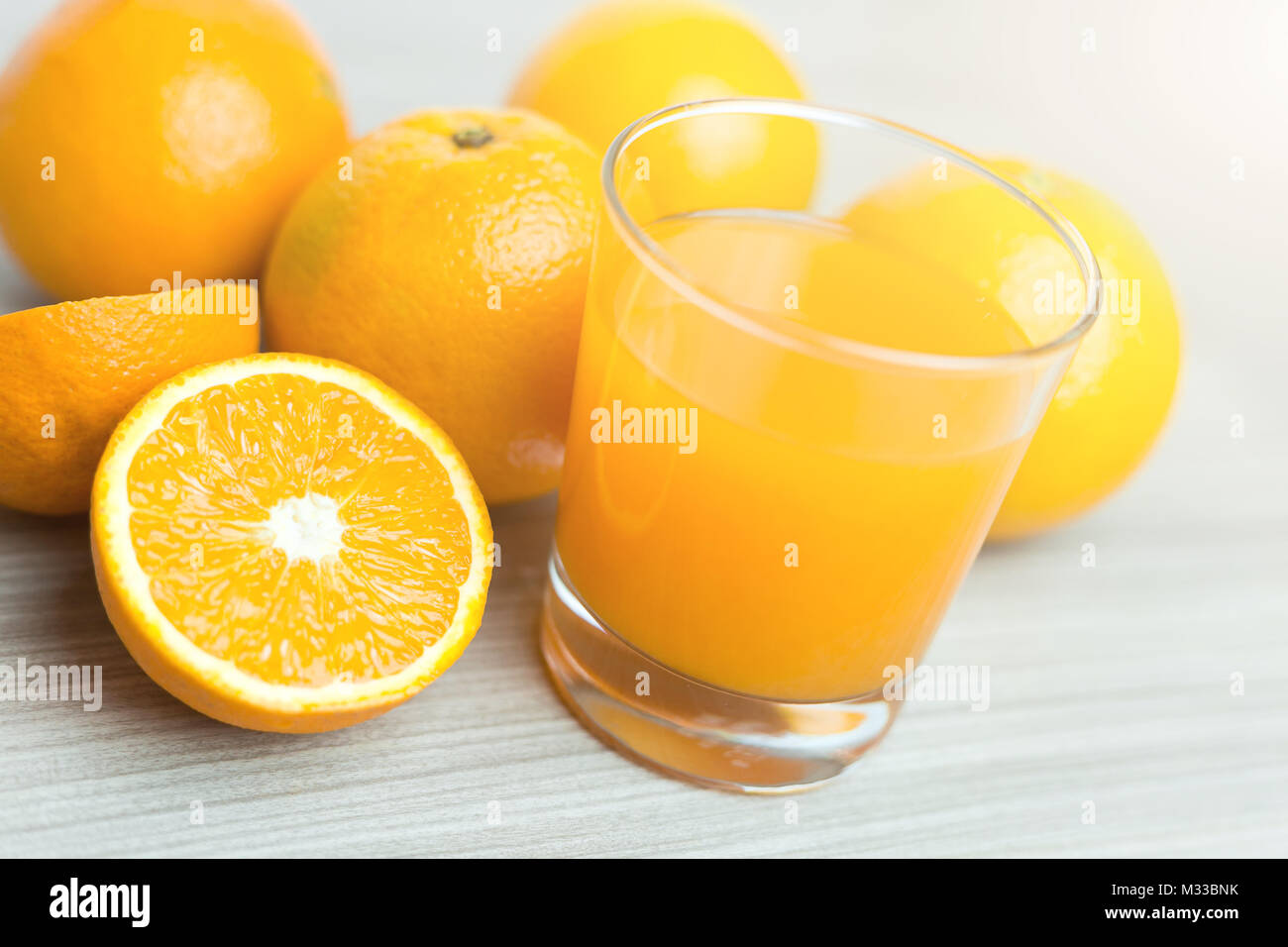 Glass of squeezed orange juice. Fresh and juicy oranges on the wooden