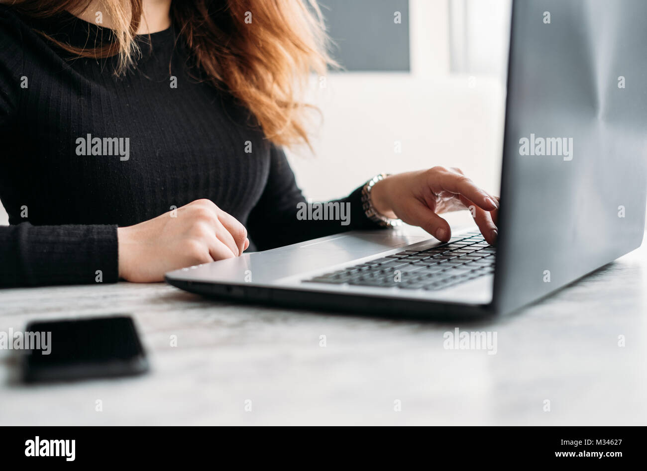 Woman sitting at a table using her laptop Stock Photo