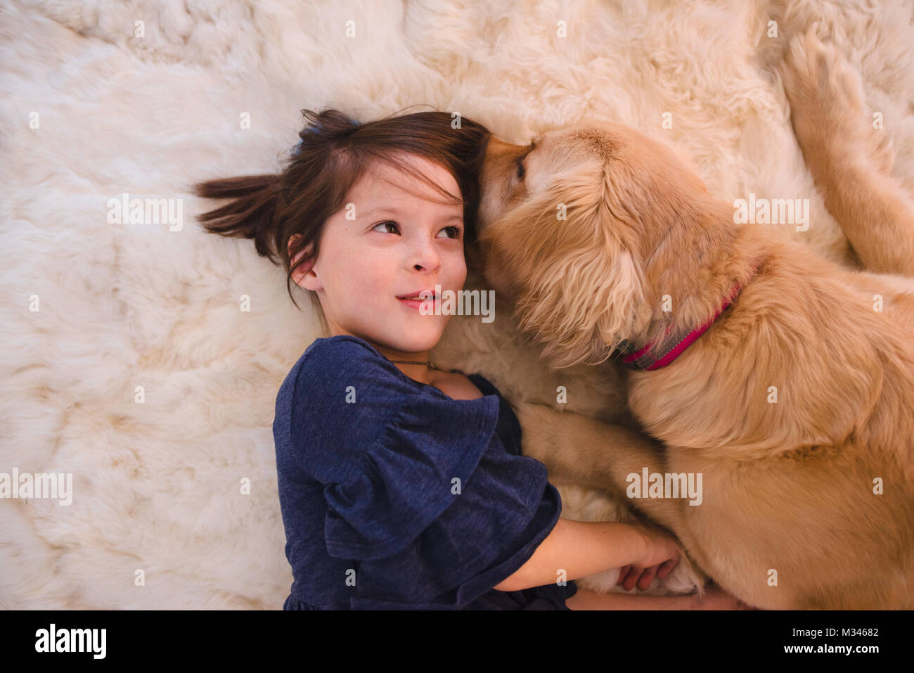 Girl lying on floor playing with her golden retriever dog Stock Photo ...