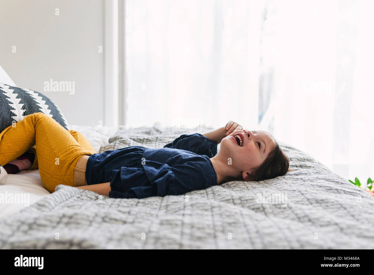 Girl lying on her bed laughing Stock Photo