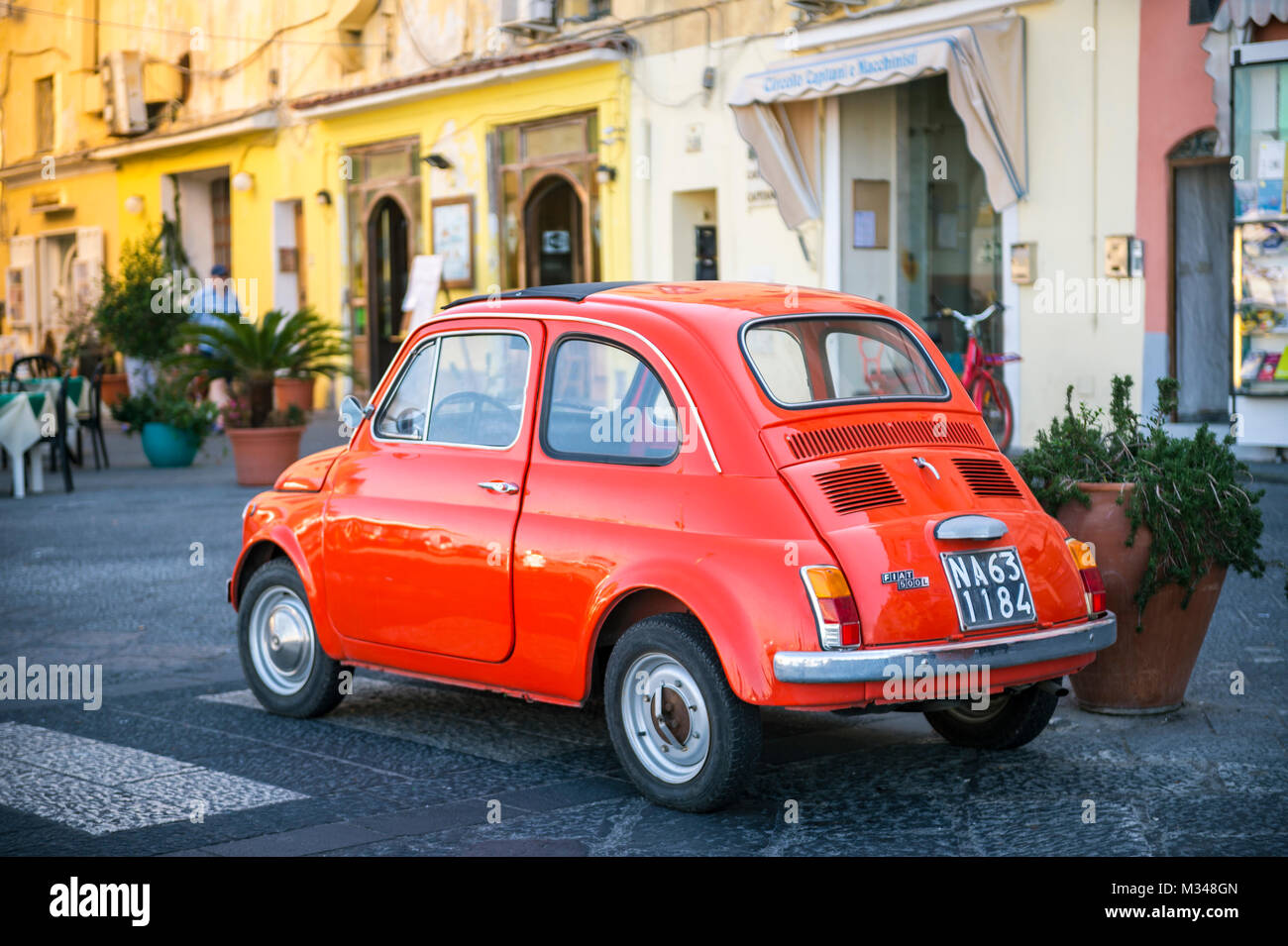 ISCHIA, ITALY - CIRCA OCTOBER, 2017: Iconic vintage tomato red Fiat 500 car parked on the harborside. Stock Photo