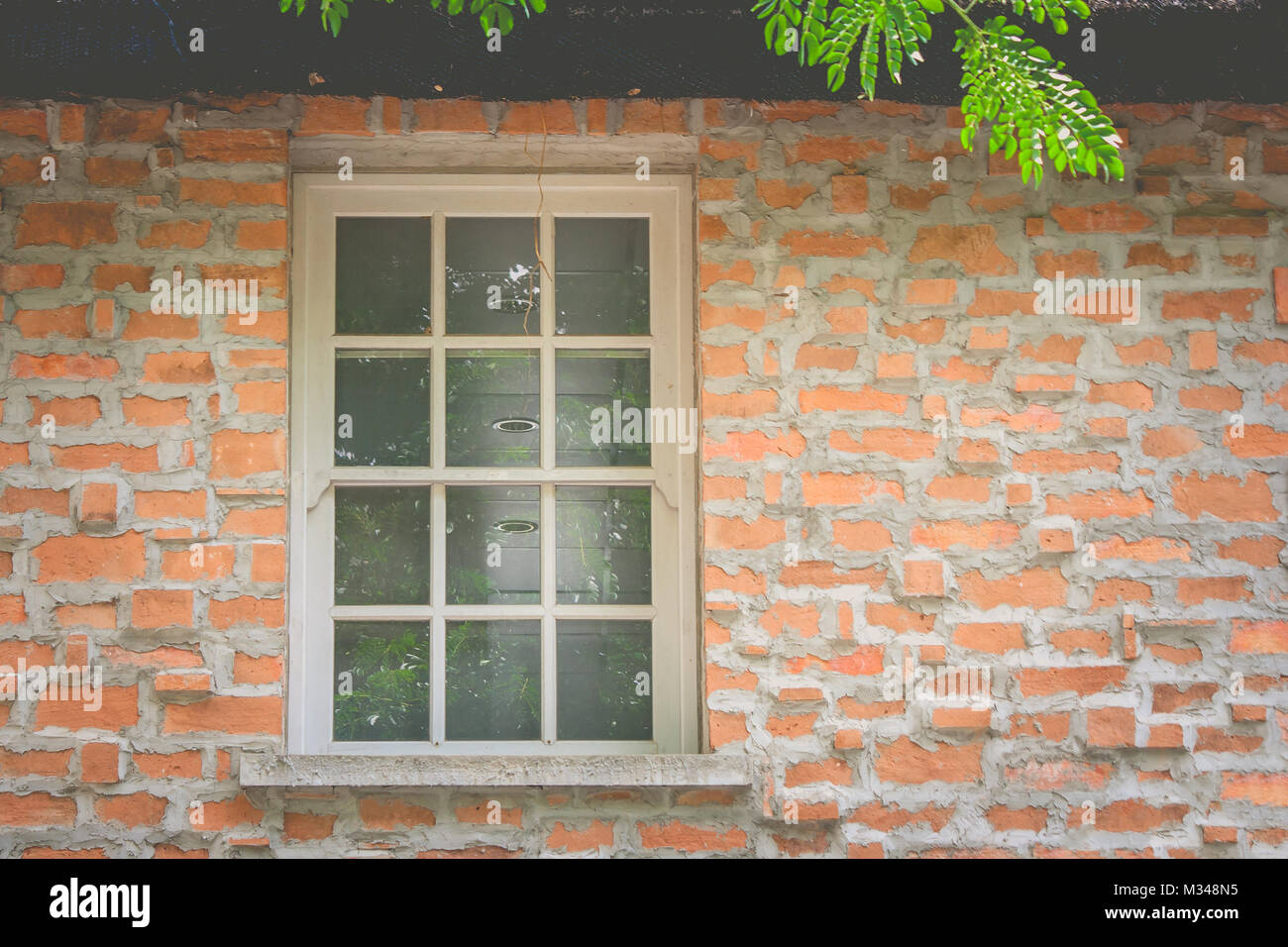 Close up old white window on brown brick wall on the top of house in ...