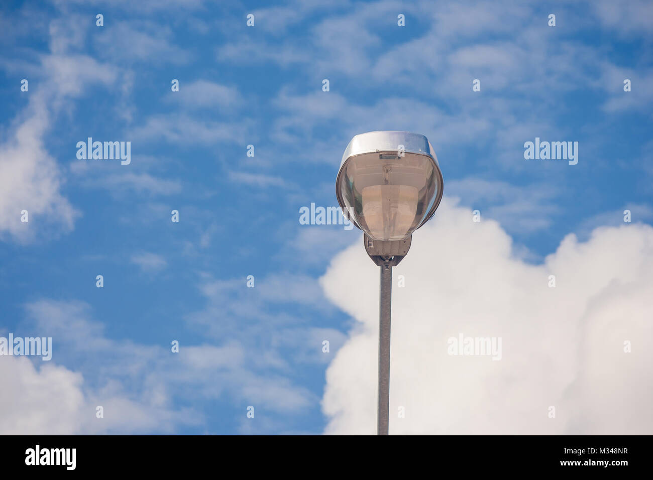 Close up of modern stree lamp located on concrete floor beside road with blue sky background. Stock Photo