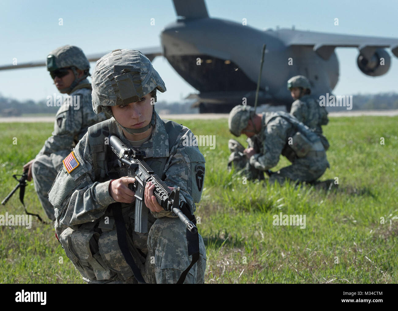 Pfc. Angela Warden from the 1st Battalion, 143rd Infantry Regiment (Airborne), provides cover for her security team during a training mission at North Texas Regional Airport in Grayson County March 28, 2015. The Austin-based Texas Army National Guard unit conducted the assault landing from a C-17 'Globemaster' at the civilian airport near Sherman, Texas. (U.S. Army National Guard photo by Staff Sgt. Mark Scovell) 36th Infantry Division Airborne Assault Landing Training by Texas Military Department Stock Photo