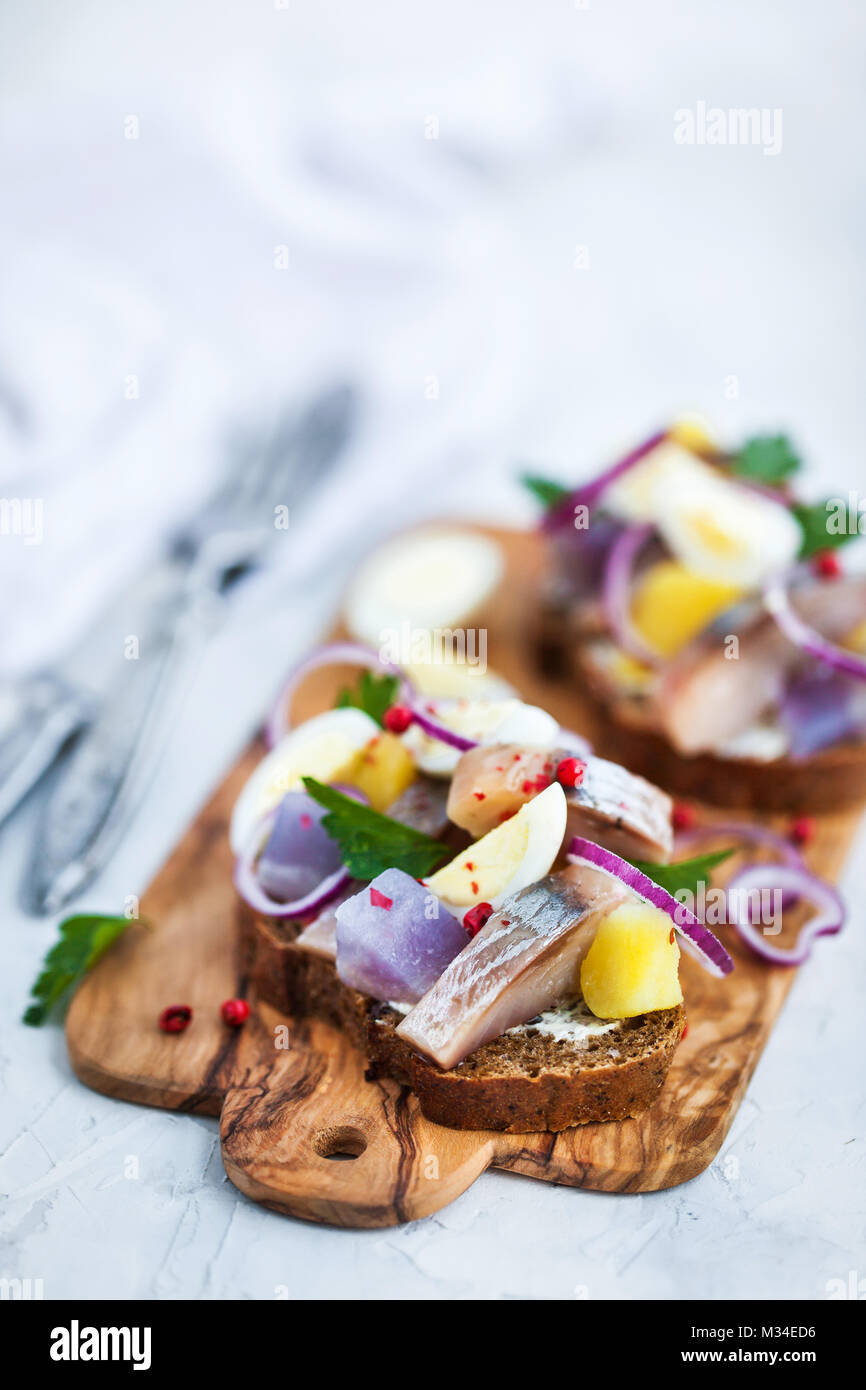 Open sandwich (smorrebrod) with herring, onion, potato and eggs Stock Photo