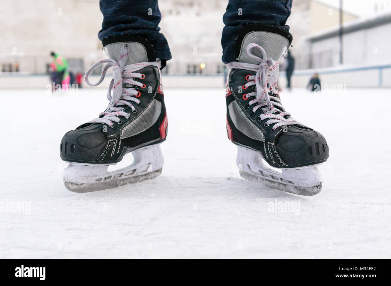 Close up of skater legs at open skating rink, front view,Mens black skates on white ice, Weekend activities outdoor in cold weather, Stock Photo