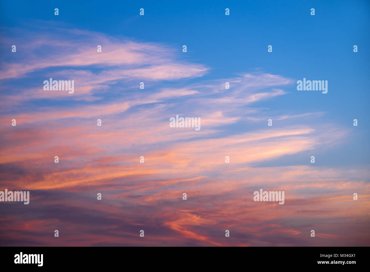 Pink and orange clouds in a blue sky at sunset Stock Photo