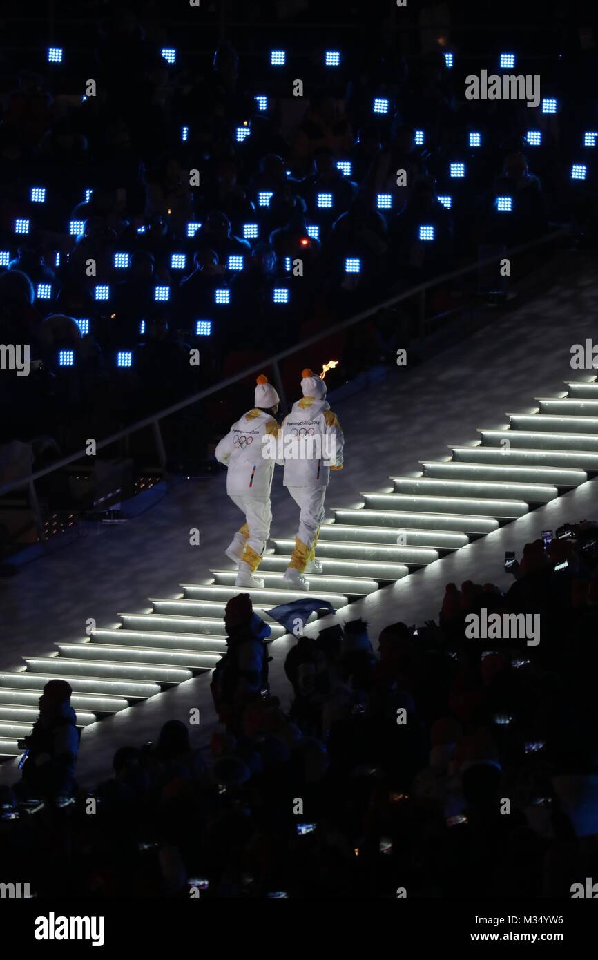February 9, 2018 - PyeongChang, South Korea - Two athletes from the Koreas' unified women's hockey team, South Korean player PARK JONG-AH and North Korean player CHUNG SU-HYON, carry the torch up the gigantic staircase during the Opening Ceremony for the 2018 Pyeongchang Winter Olympic Games, held at PyeongChang Olympic Stadium. (Credit Image: © Scott Mc Kiernan via ZUMA Wire) Stock Photo