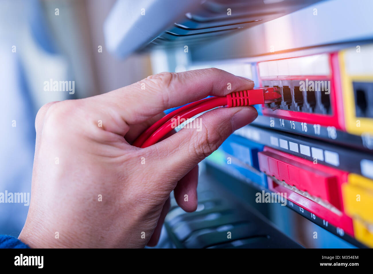 administrator holding network cables connected to servers Stock Photo