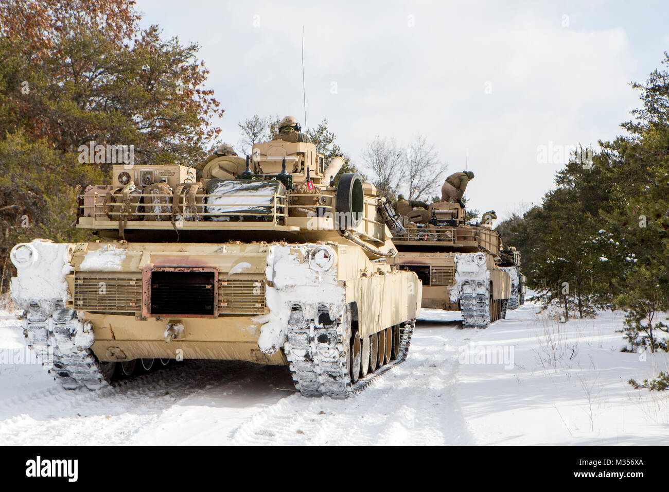 Marines with Company F, 4th Tank Battalion, 4th Marine Division, pause before convoying to a training area during exercise Winter Break 2018 near Camp Grayling, Michigan, Feb. 8, 2018. During training day two of Winter Break 18, Fox Co. Marines rehearsed formations, conducted advanced land navigation and terrain identification and performed preventative maintenance checks and services on their armored vehicles and equipment while increasing their operational capacity in single degree temperatures and snow covered terrain. Stock Photo