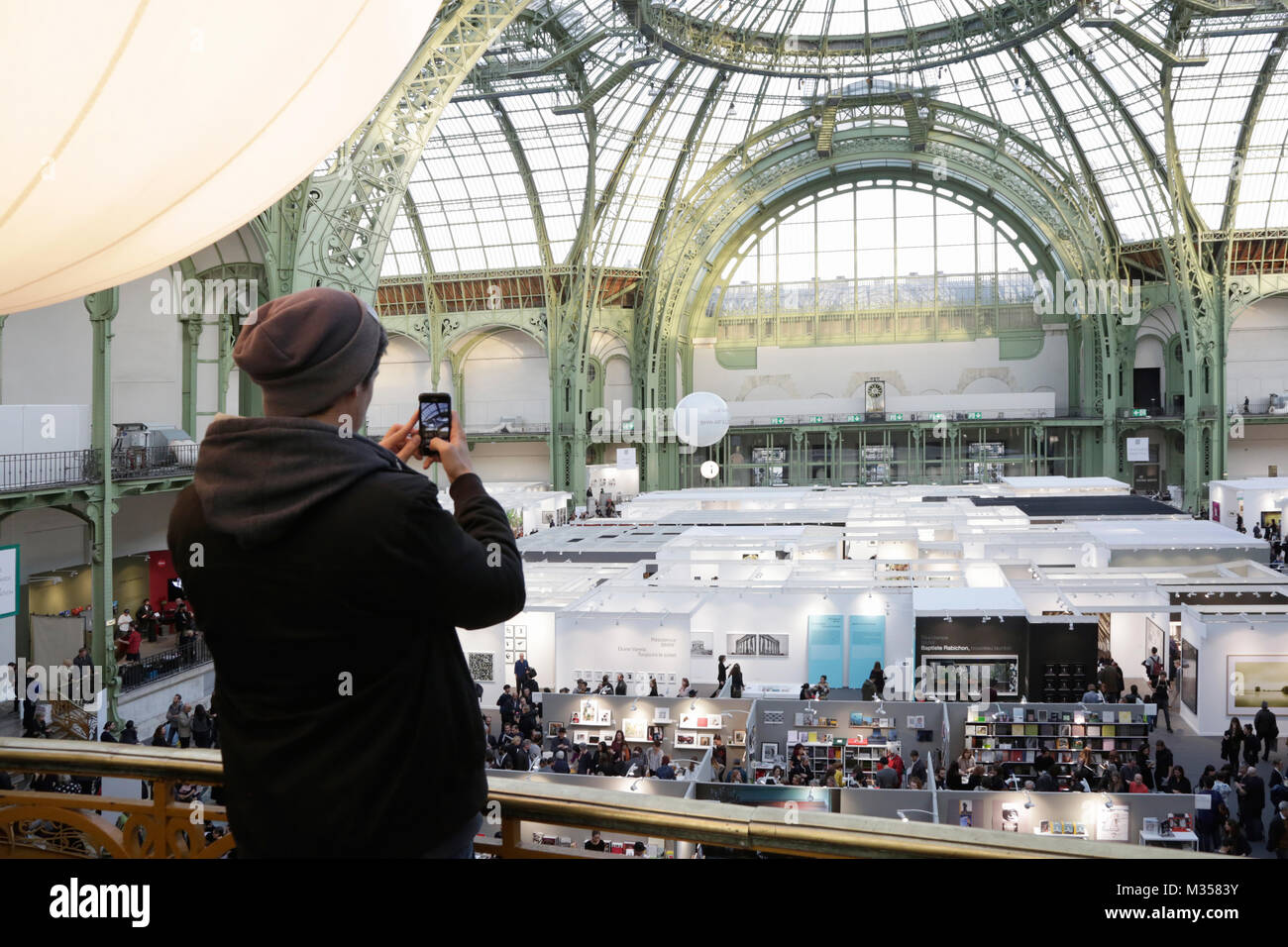 PARIS - NOVEMBER 10: Man shooting photo with phone during Paris Photo art fair at Grand Palais on November 10, 2017 in Paris, France. Stock Photo