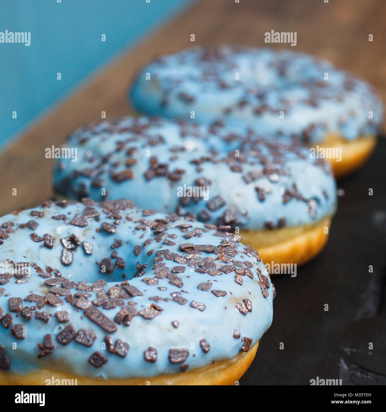 Three donuts with atypical coloring - blue icing and silver chocolate ...