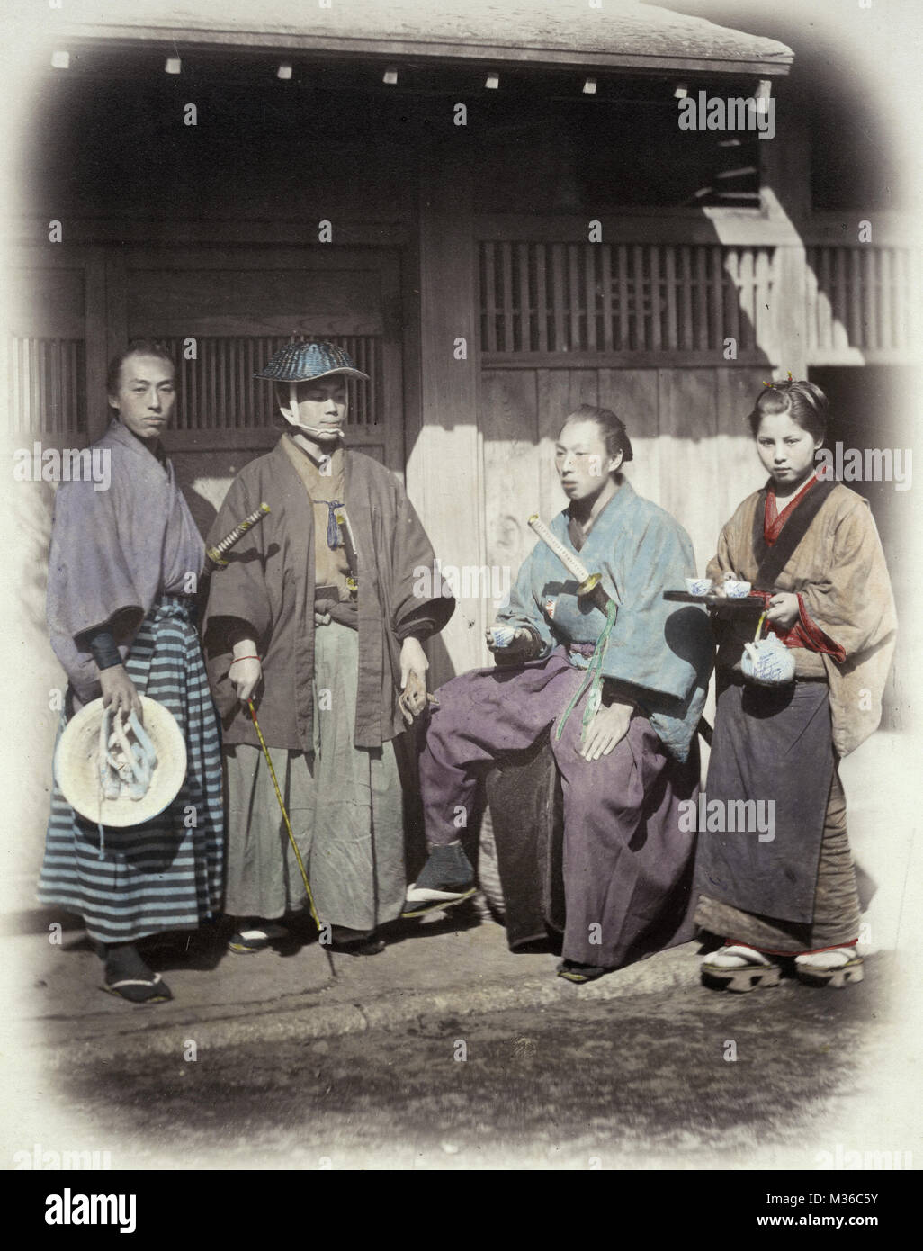 1860's Japan - portrait of a samurai group being served by a tea house servant Stock Photo