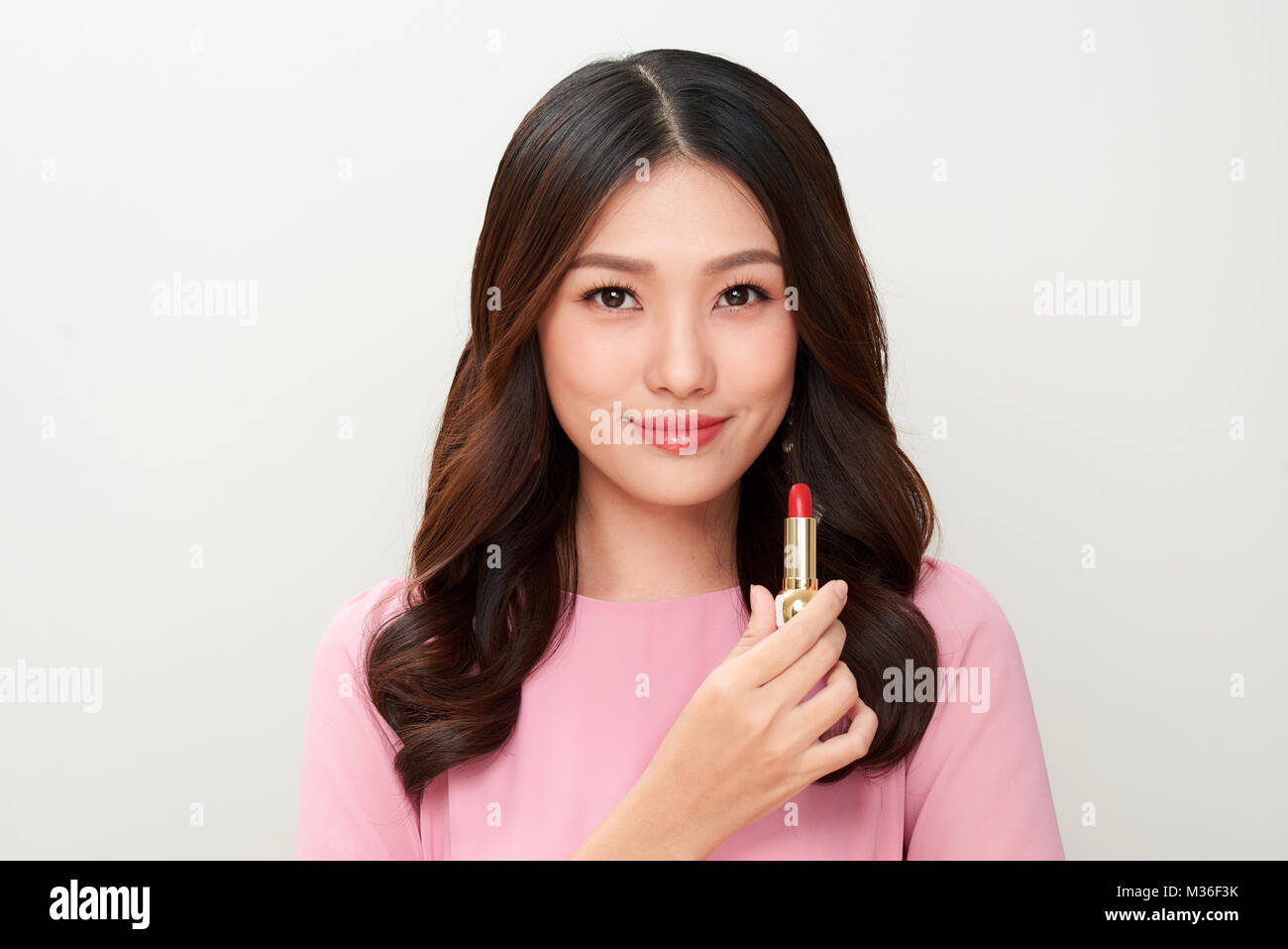 Beautiful asian woman holding red lipstick and applying it Stock Photo