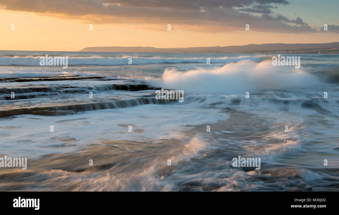 Dramatic Powerful waves crashing with power on sea rock plates during sunset. Akrotiri area, Limassol, Cyprus Stock Photo